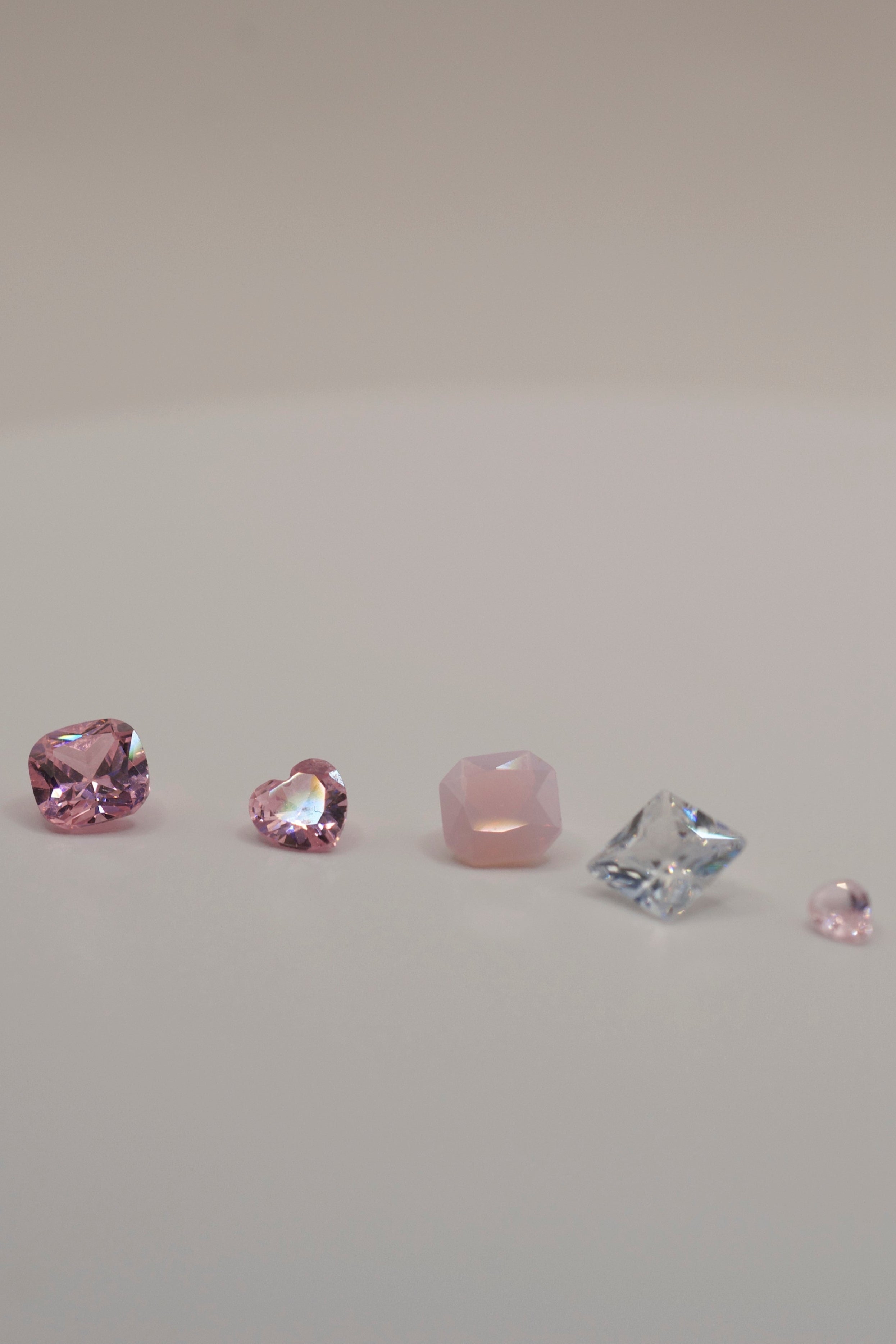 Gemstones for lost wax casting and cast in place jewellery — pink, blush, and clear faceted stones in cushion, heart, hexagon, princess, and pear cuts.