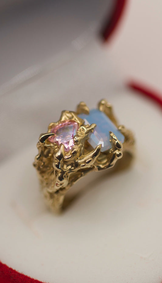 Detailed view of a lost wax ring with an emerald-cut lab grown opal, light pink cubic zirconia heart, and intricate gothic claw settings, crafted in solid 9ct gold or sterling silver.