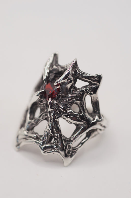 gothic web engagement ring with high polish, and a red heart shape garnet stone. Handmade using the lost wax technique. Recycled eco friendly 925 sterling silver. Alternative designs and a high quality ring front view. Grunge jewellery.