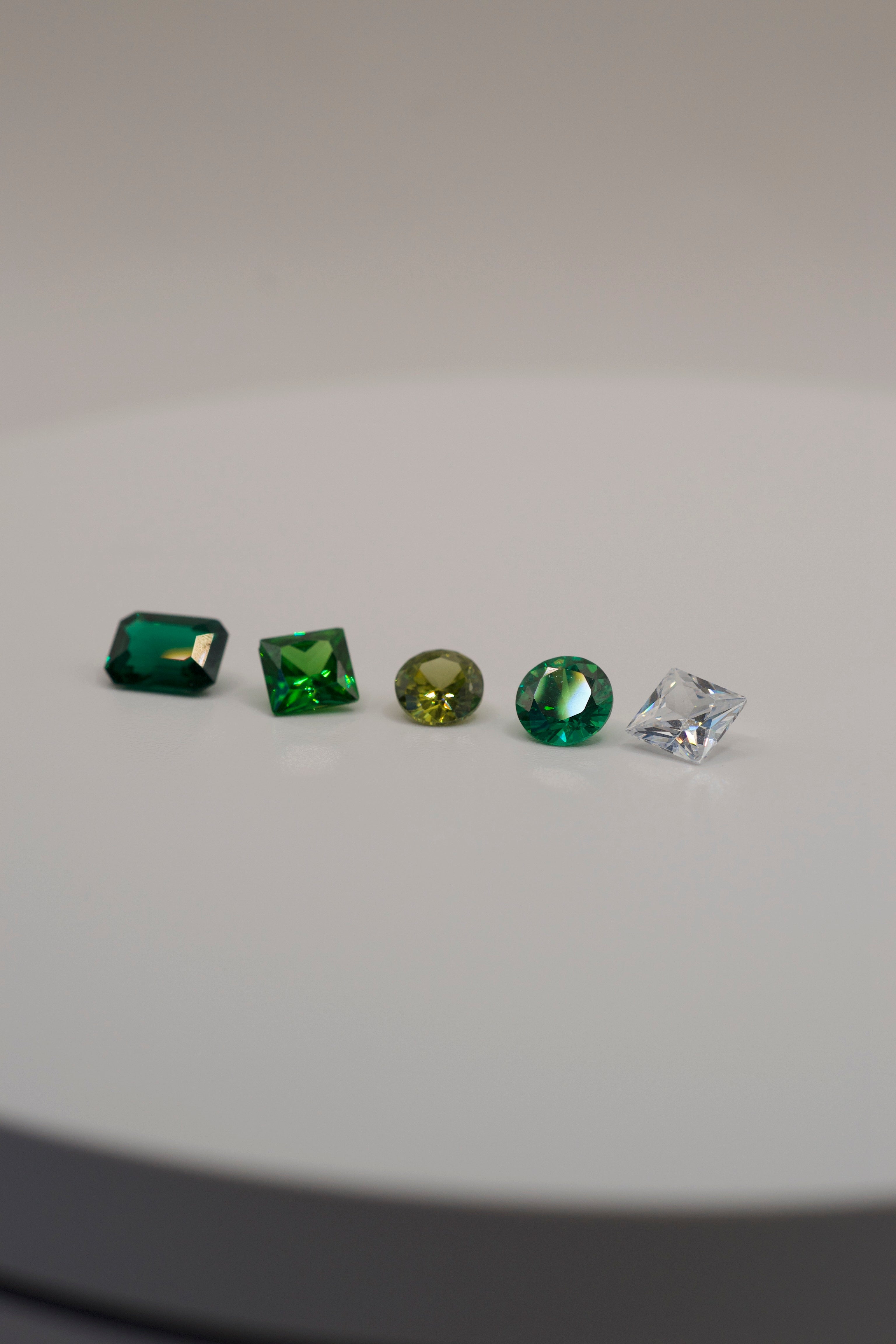 Loose faceted gemstones in green and clear tones, perfect for lost wax carving and casting in place designs.