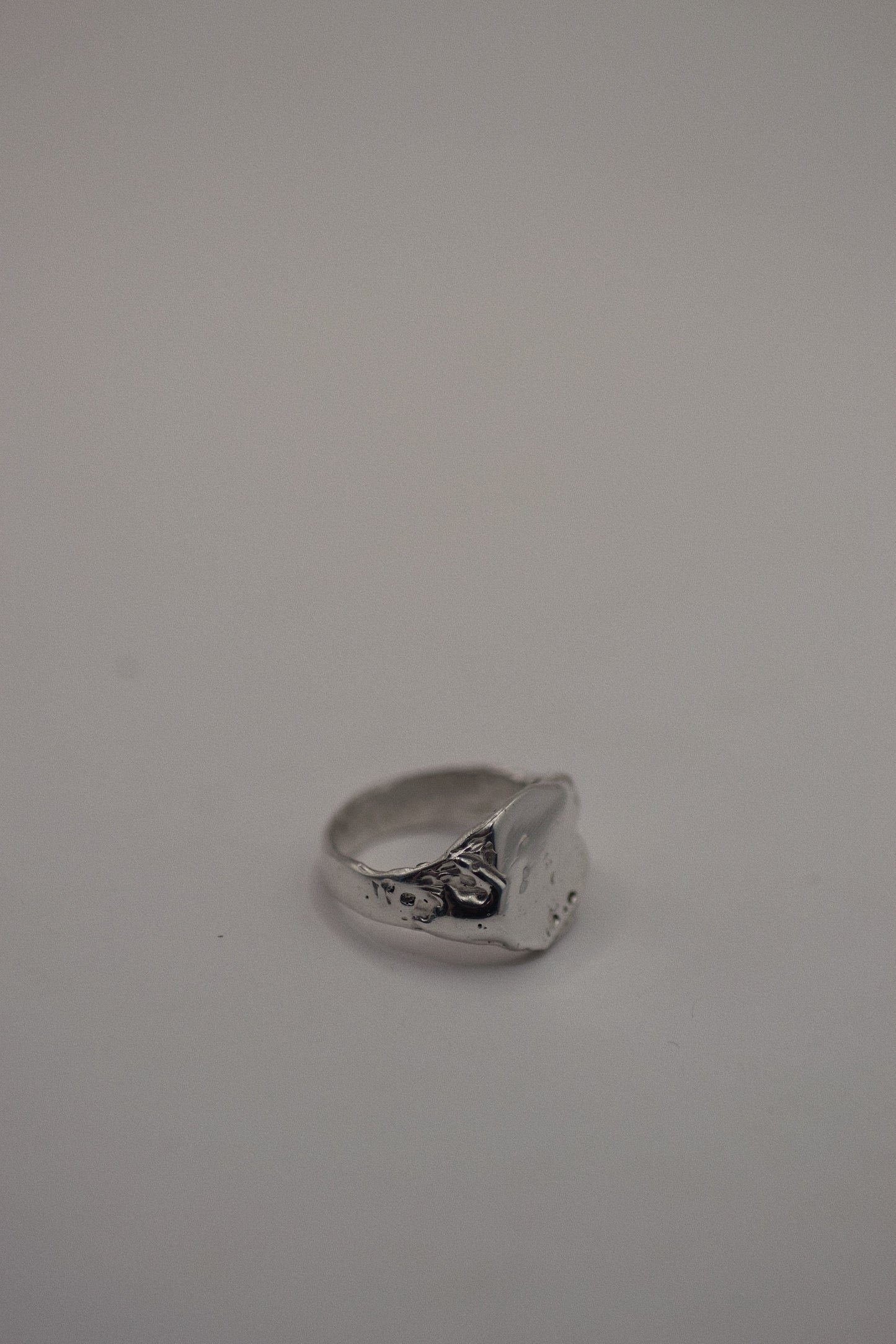 This 925 sterling silver signet ring is sculpted with organic dips and grooves that add dimension and texture to the flat surface. The smooth, sleek band complements the rugged finish, where dips and subtle craters are designed to evoke a natural, earthy look. Made using the lost wax method, this ring showcases the beauty of handcrafted silver, with each piece carrying its own unique texture and character.