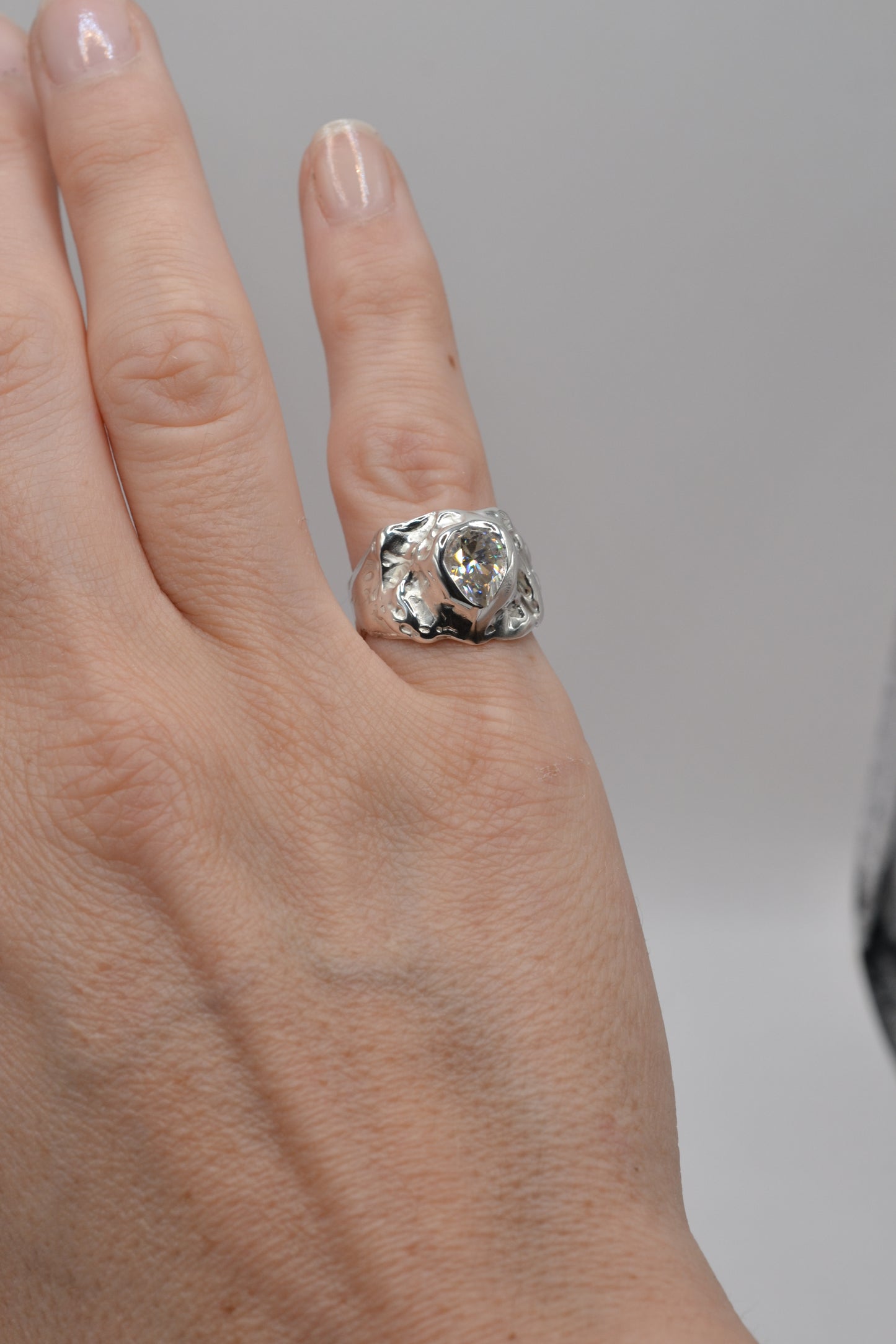 Full-hand view of the molten silver pear-cut moissanite ring, demonstrating size, presence, and alternative jewellery style.