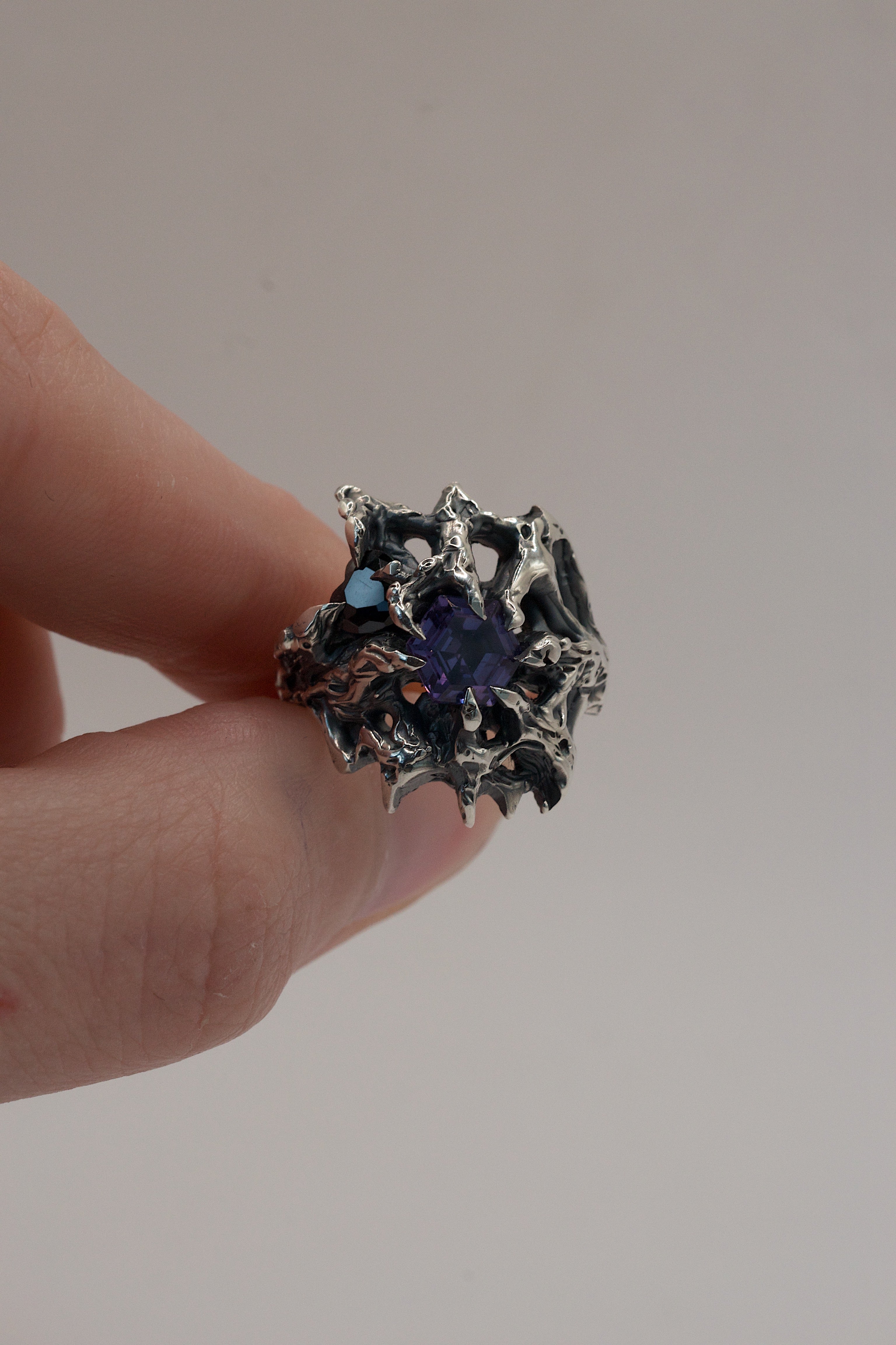 Alternative silver ring featuring a claw-set heart cubic zirconia and a hex alexandrite, textured with a raw molten finish.