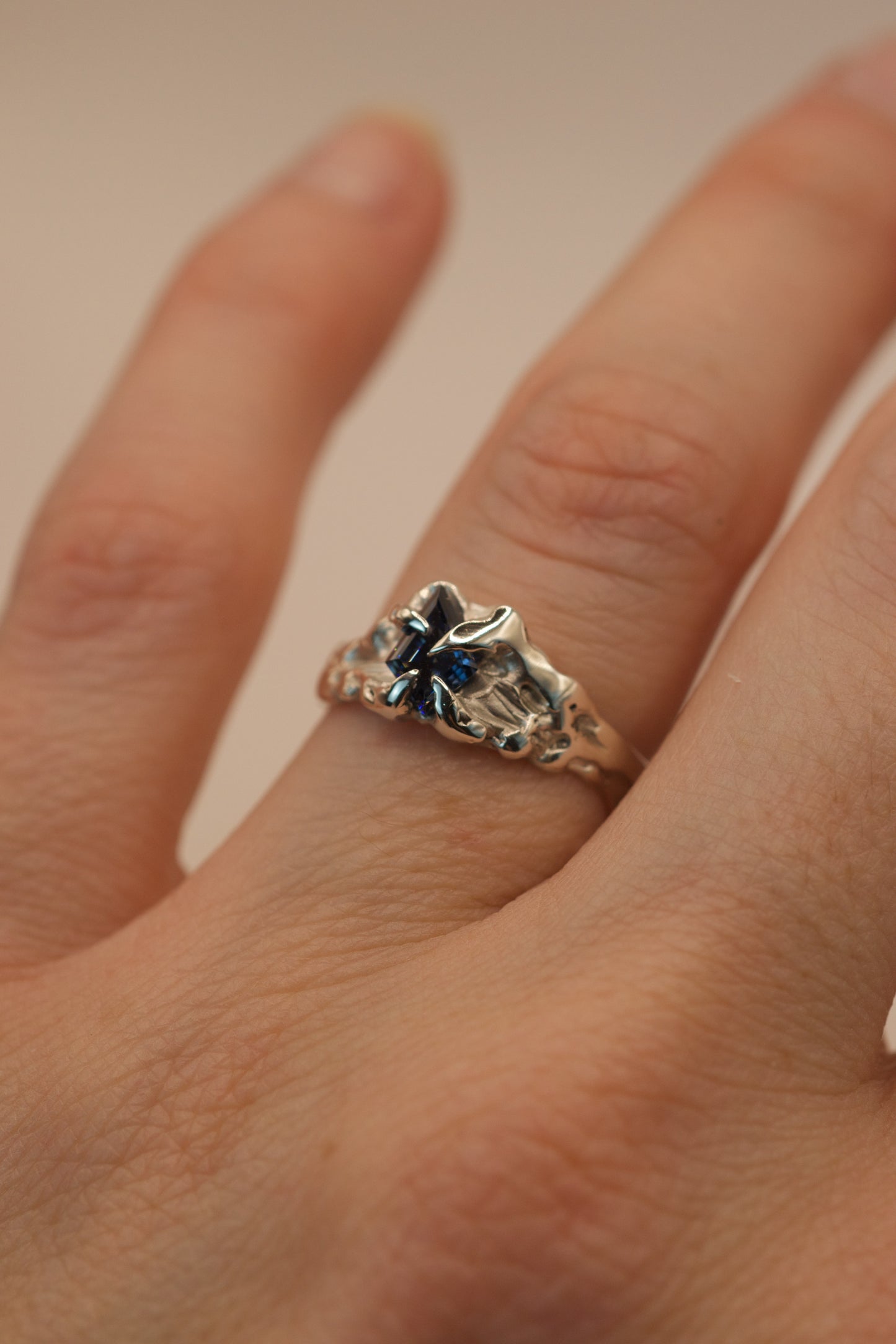 A unique one of a kind sterling silver ring with molten, textured details. The vivid blue kite cut moissanite is held securely by gothic inspired claws in this handmade lost wax design.