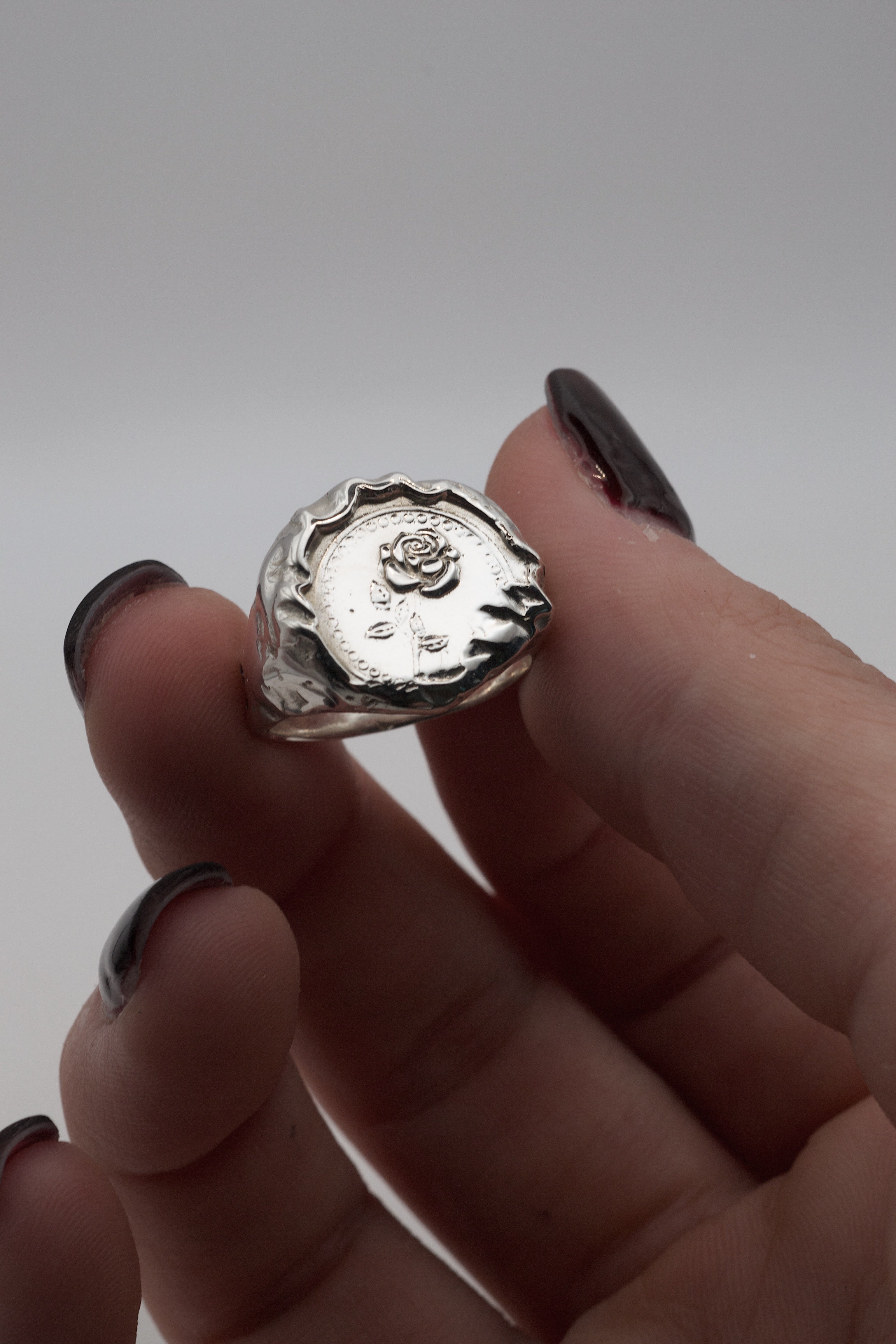 Handmade molten silver signet ring in an alternative gothic style, created using the lost wax jewellery making process with an embossed rose centre.