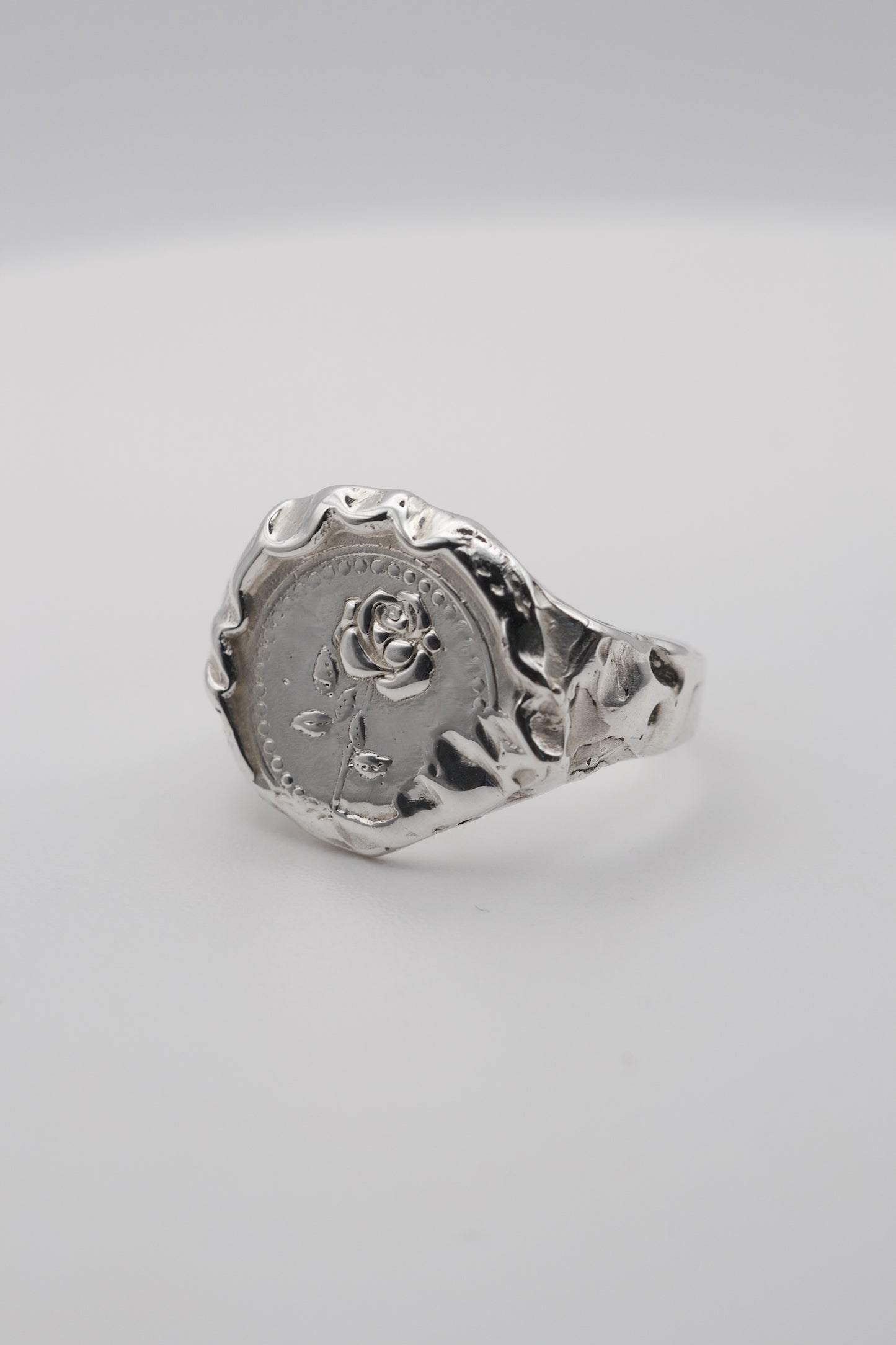 Handmade molten silver signet ring created using the lost wax technique, featuring an embossed rose design and organic molten texture edges in an alternative gothic style.