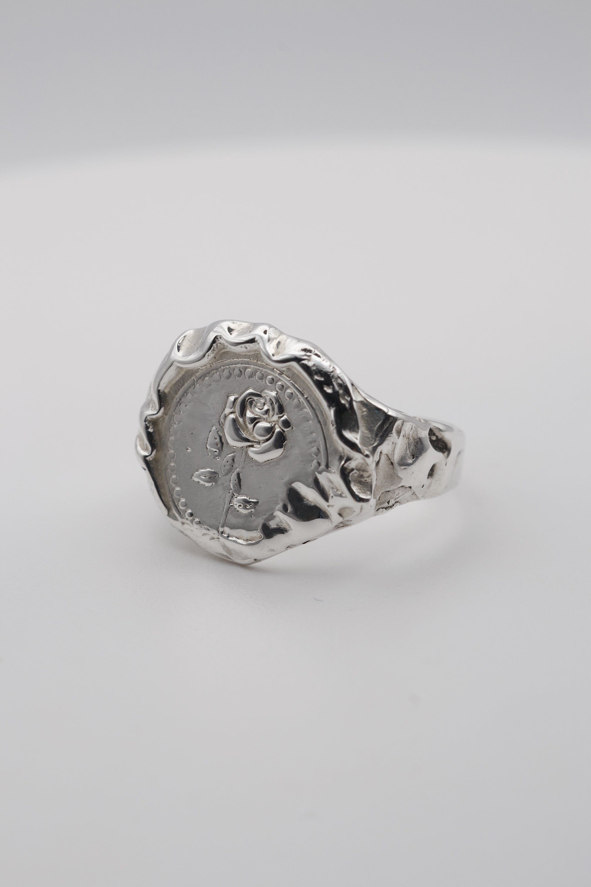 Handmade molten silver signet ring created using the lost wax technique, featuring an embossed rose design and organic molten texture edges in an alternative gothic style.