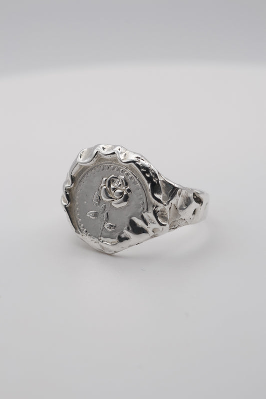 Handmade molten silver signet ring created using the lost wax technique, featuring an embossed rose design and organic molten texture edges in an alternative gothic style.