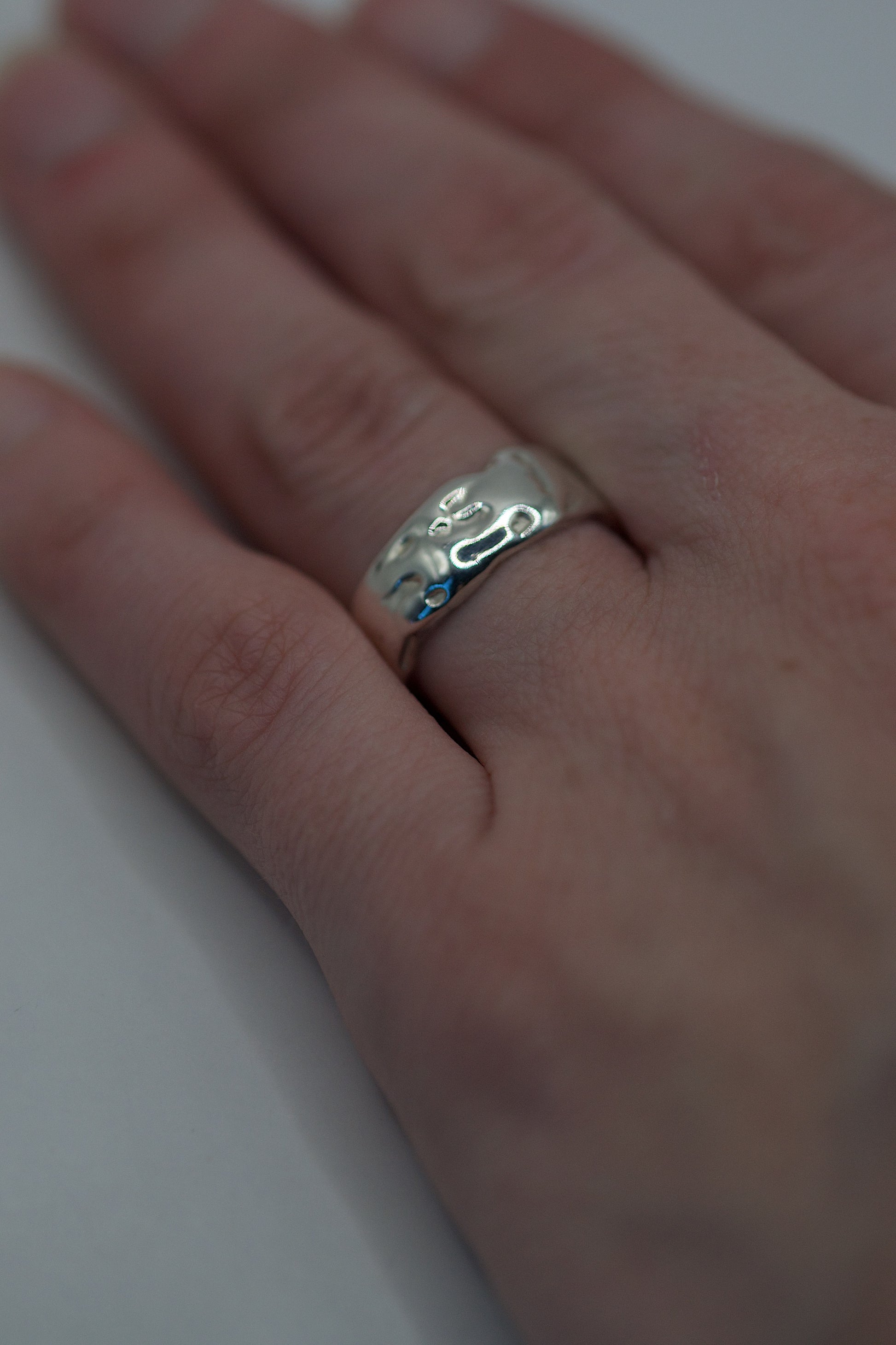Worn view of organic handmade silver ring with flowing molten texture from lost wax casting process