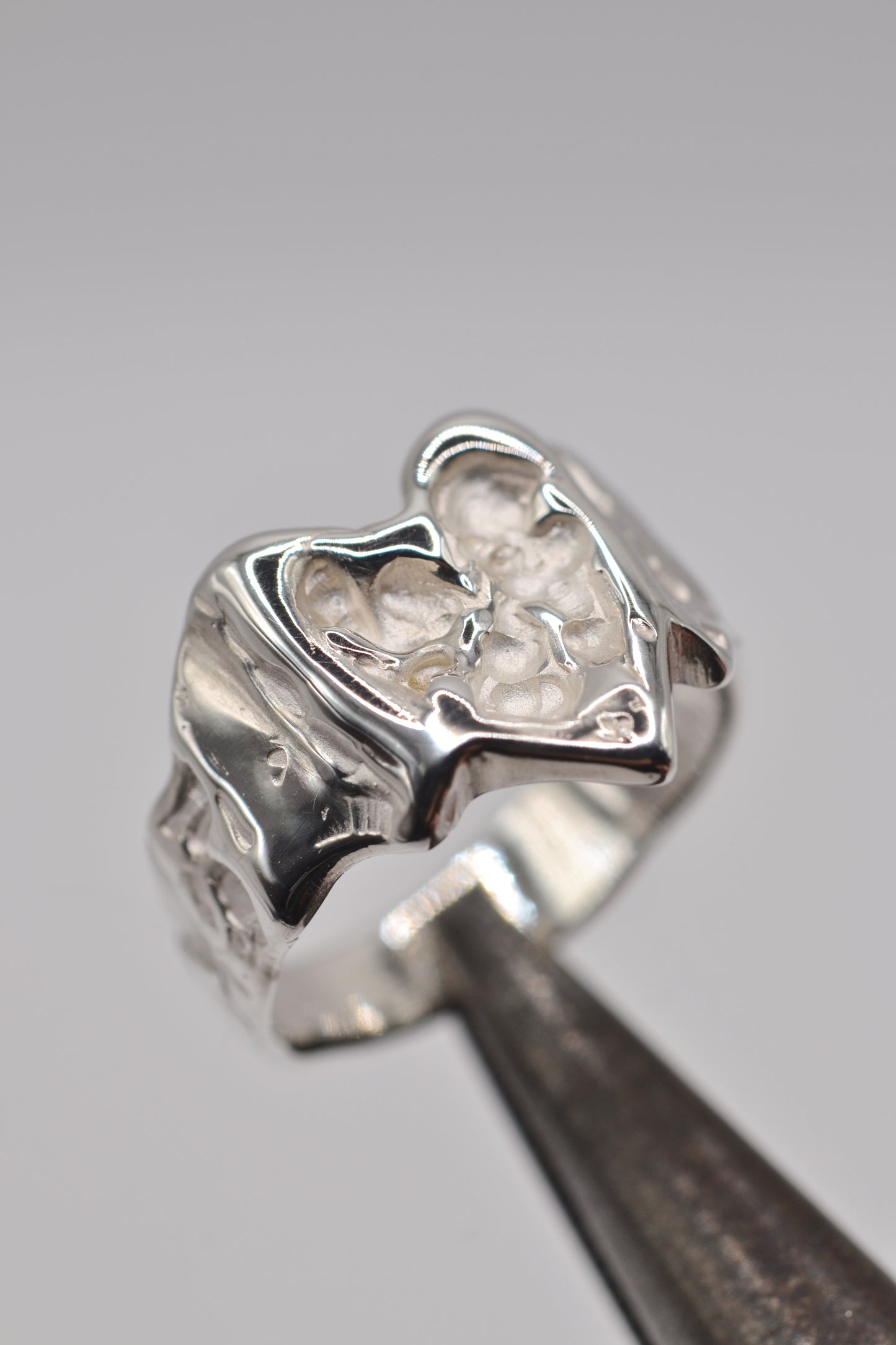 Organic lost wax cast ring in sterling silver photographed on metal tool, molten heart ring with organic texture