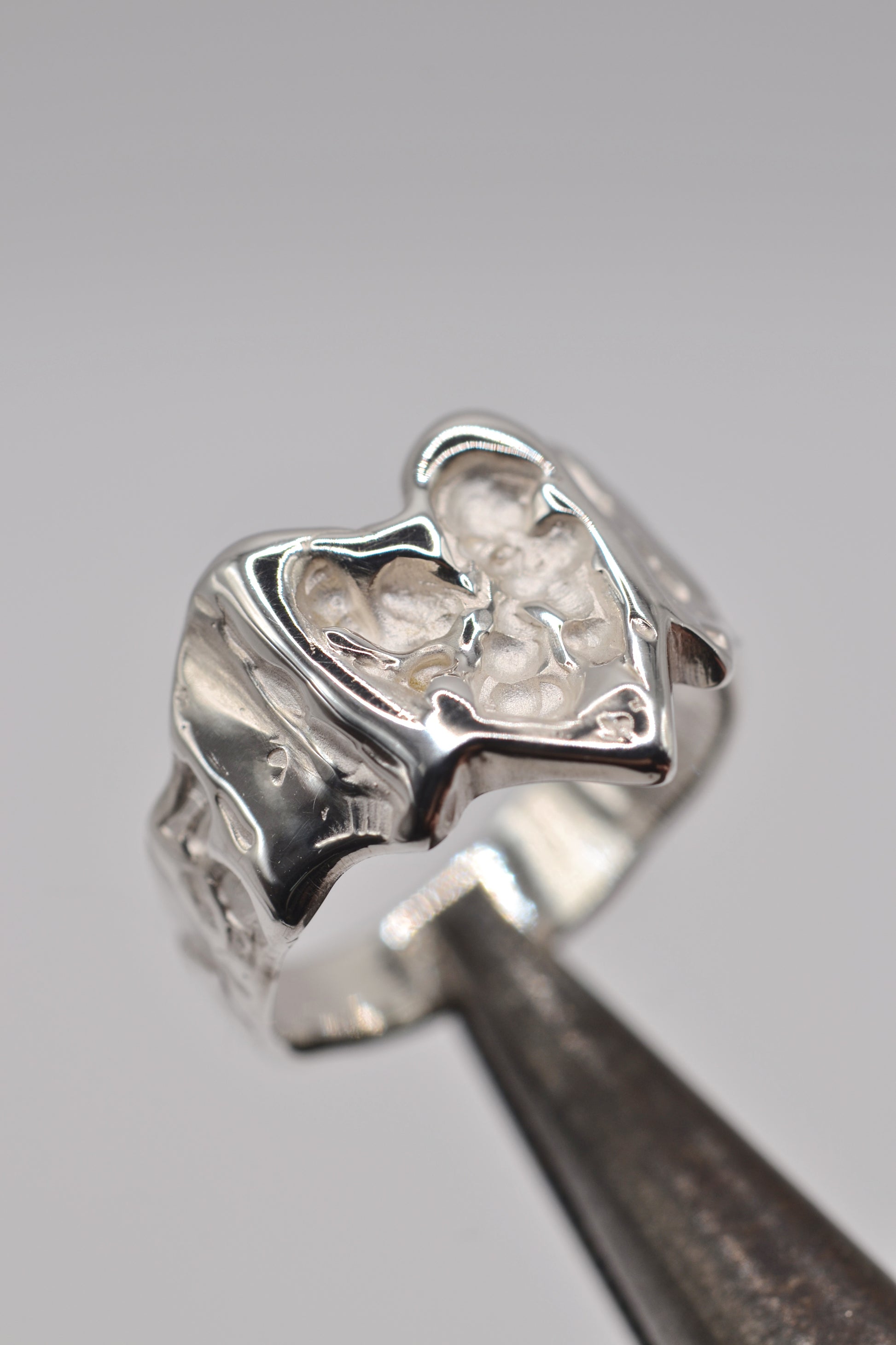 Organic lost wax cast ring in sterling silver photographed on metal tool, molten heart ring with organic texture