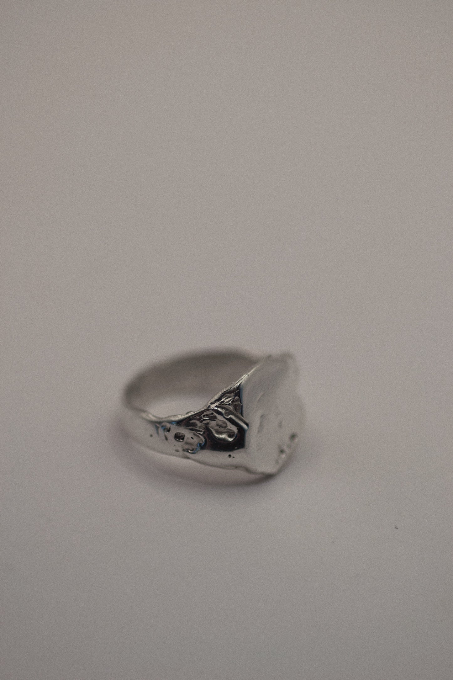 This handmade 925 sterling silver signet ring features organic dips and grooves, giving it a rugged yet elegant appeal. Created using the lost wax method, this ring has an earthy, sculpted look that blends sleek sophistication with a touch of grunge. Perfect for those who appreciate unique, handcrafted silver jewelry.