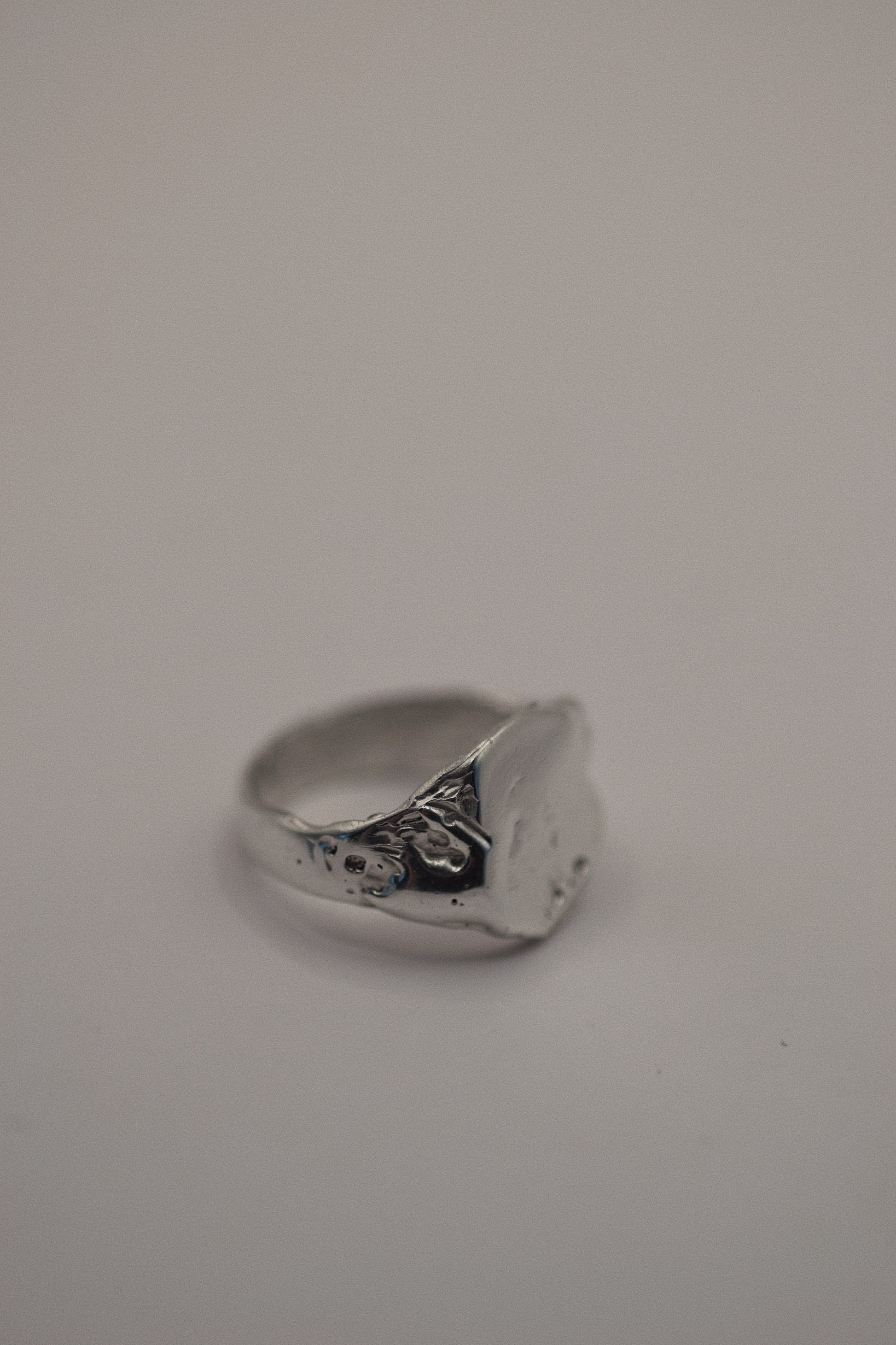 This handmade 925 sterling silver signet ring features organic dips and grooves, giving it a rugged yet elegant appeal. Created using the lost wax method, this ring has an earthy, sculpted look that blends sleek sophistication with a touch of grunge. Perfect for those who appreciate unique, handcrafted silver jewelry.