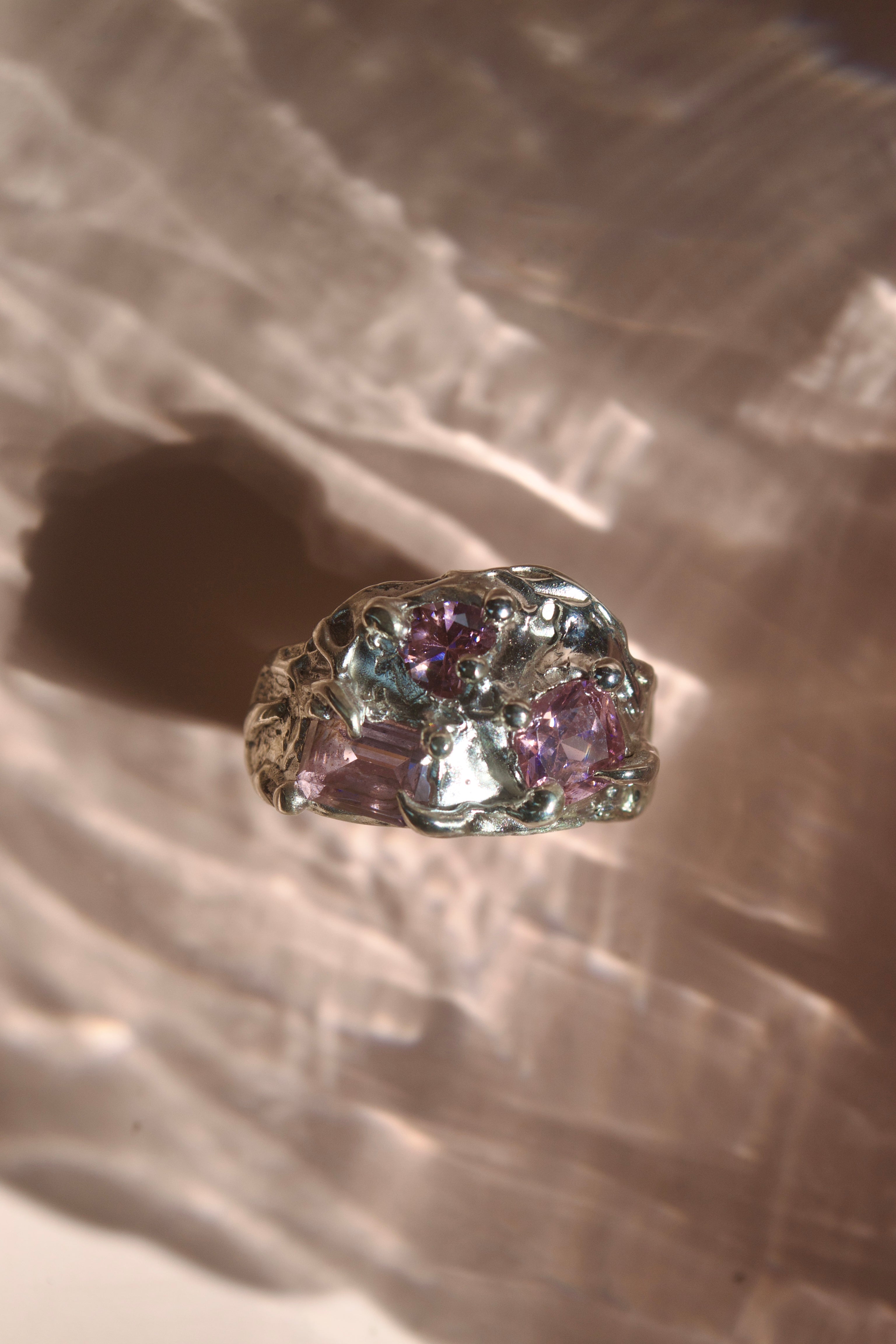 Lost wax molten silver cluster ring with curves and melting look. Three light pink crystals - heart, square and cushion shaped. Chunky top of ring. Organic textured & Y2K aesthetic jewellery.