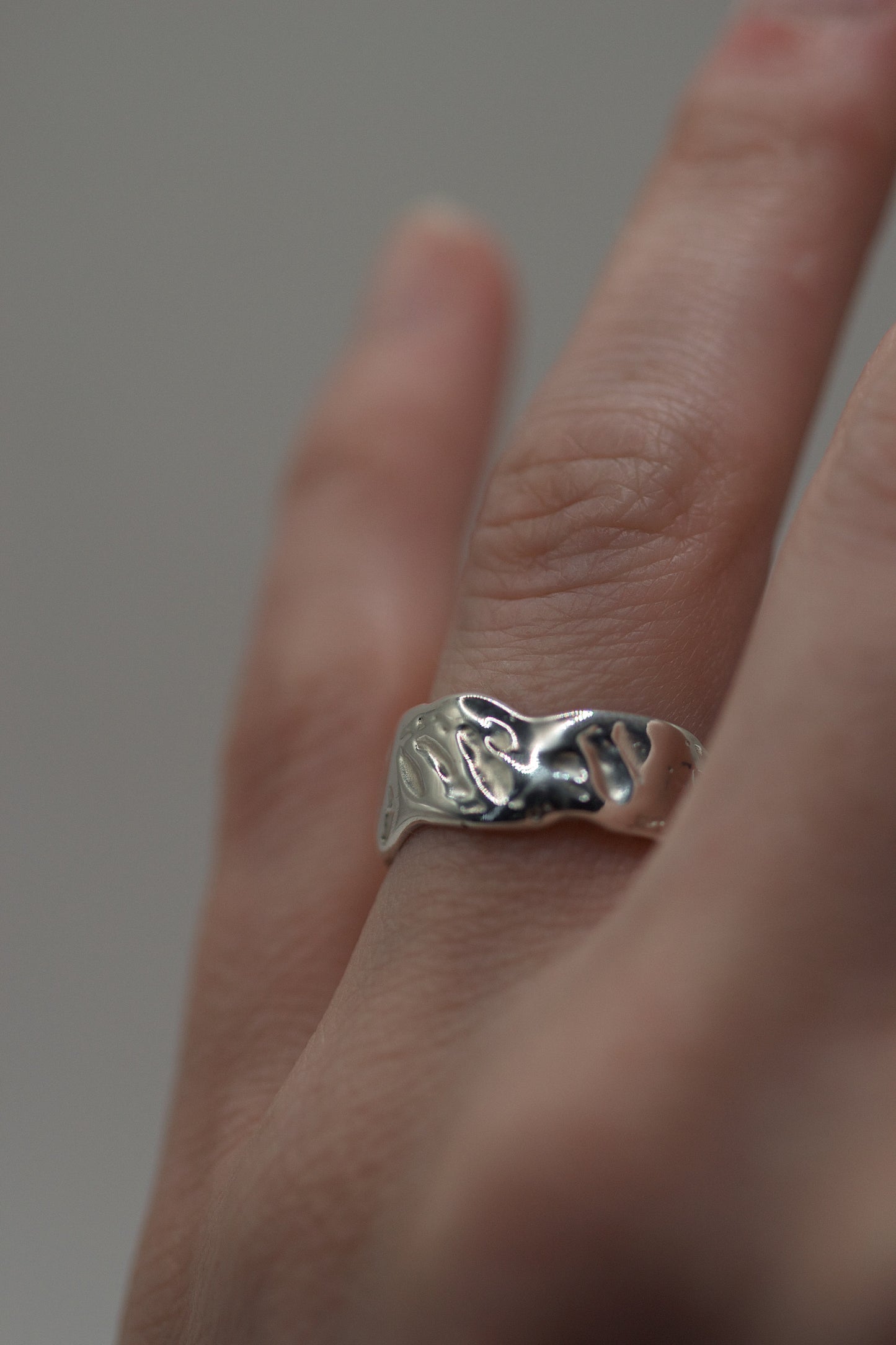 Handmade silver ring with molten texture and sculptural form worn on finger, created using the lost wax casting technique