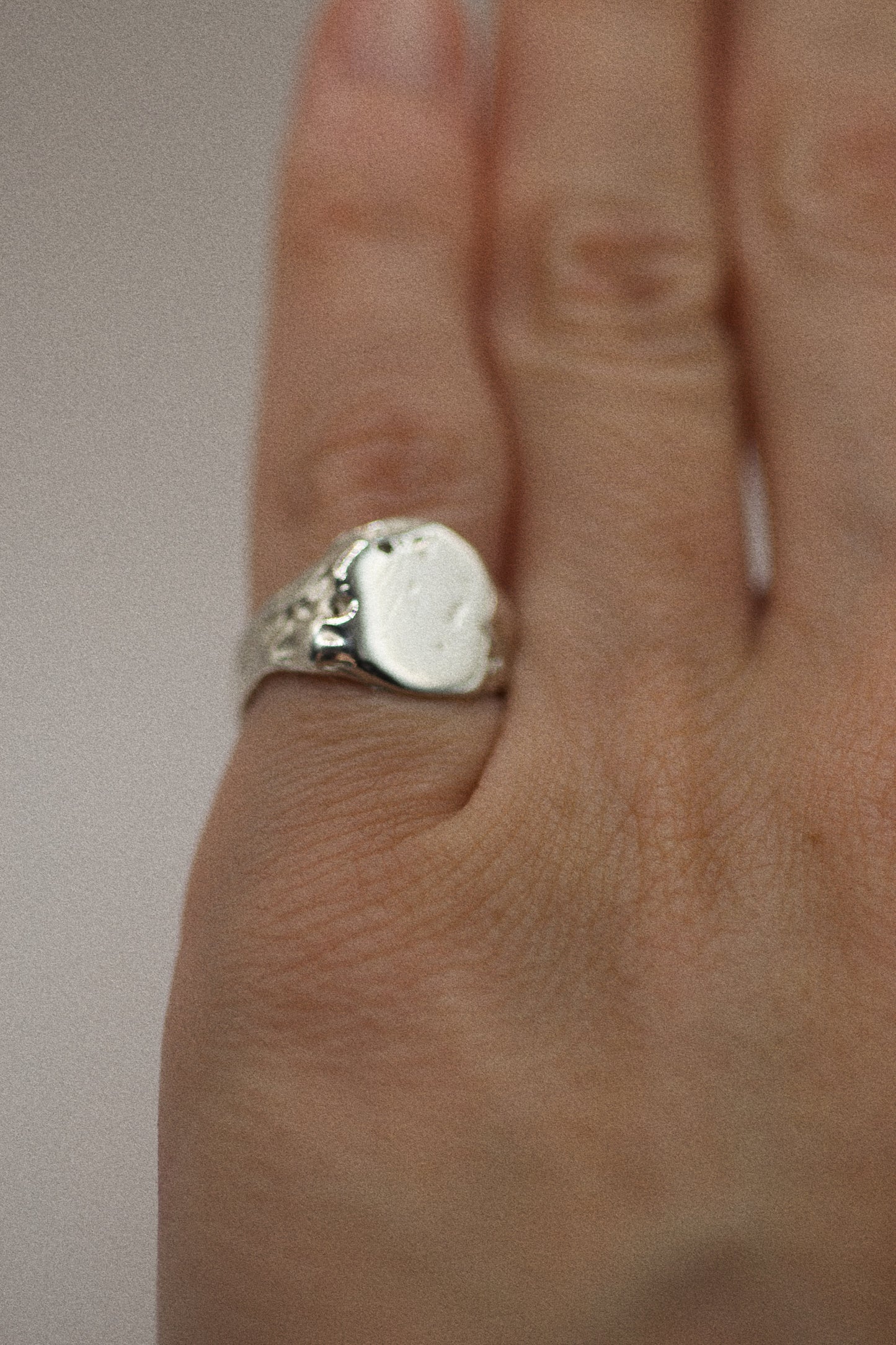 Crafted from 925 sterling silver, this signet ring features an earthy, organic design with dips and grooves across the surface. The band remains smooth and sleek, balancing the rougher, textured elements. With its sculpted, uneven finish, including small craters, this ring embodies a raw, rugged appeal. Created using the lost wax method, each ring is a unique interpretation of the natural world, combining elegance with a grunge-inspired feel.