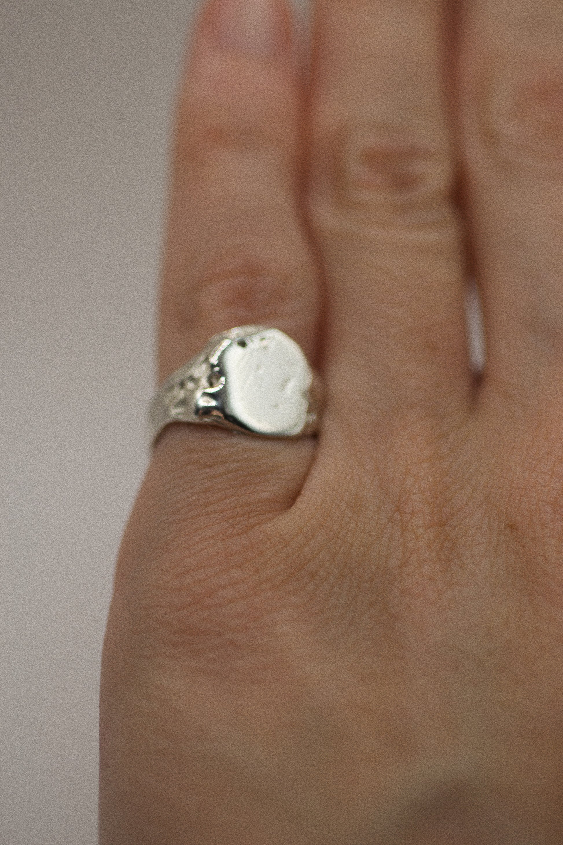 Crafted from 925 sterling silver, this signet ring features an earthy, organic design with dips and grooves across the surface. The band remains smooth and sleek, balancing the rougher, textured elements. With its sculpted, uneven finish, including small craters, this ring embodies a raw, rugged appeal. Created using the lost wax method, each ring is a unique interpretation of the natural world, combining elegance with a grunge-inspired feel.