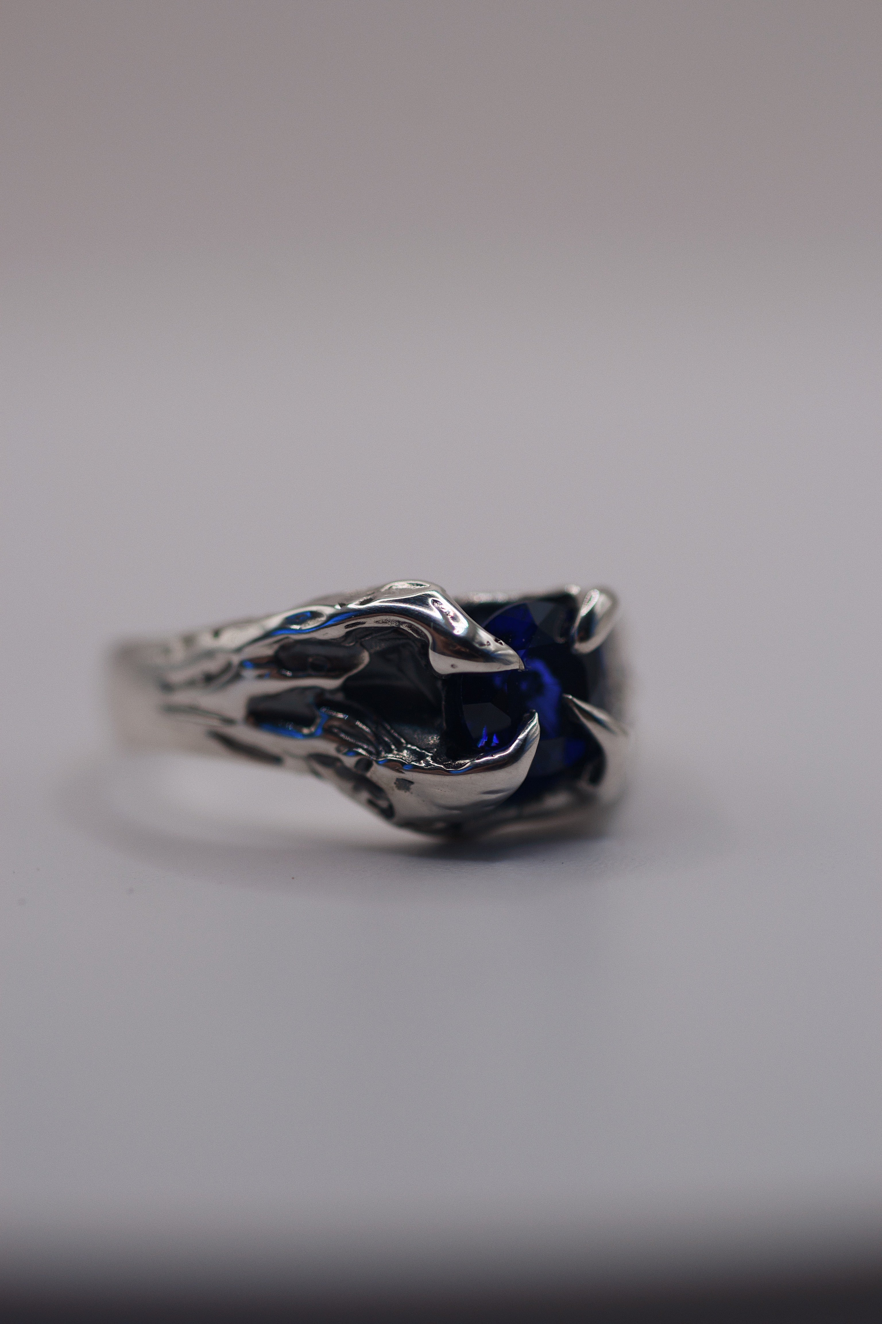  A one-of-a-kind gothic-inspired silver ring with a round sapphire centerpiece, handcrafted through wax carving and casting.