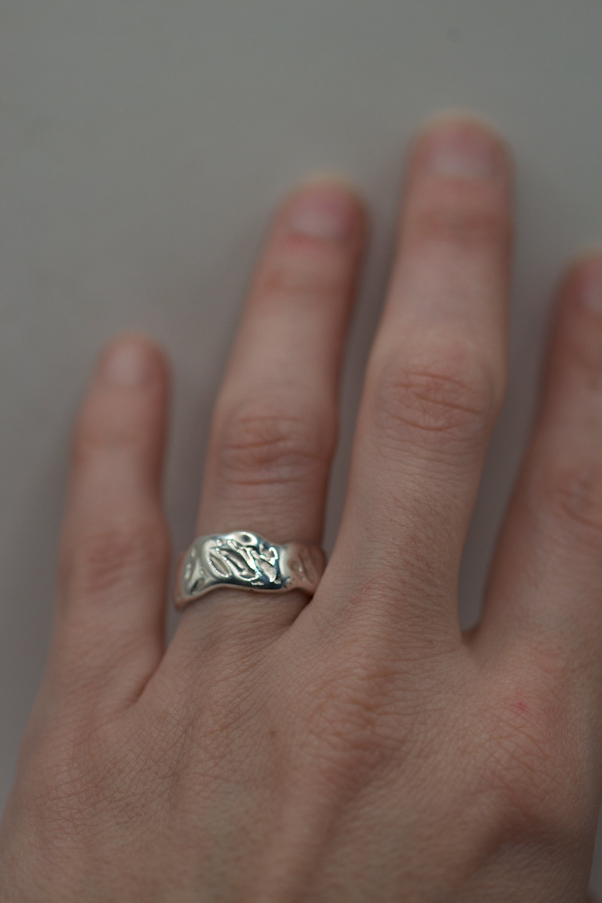 Handmade silver ring with organic molten surface worn on hand, created using the lost wax casting method