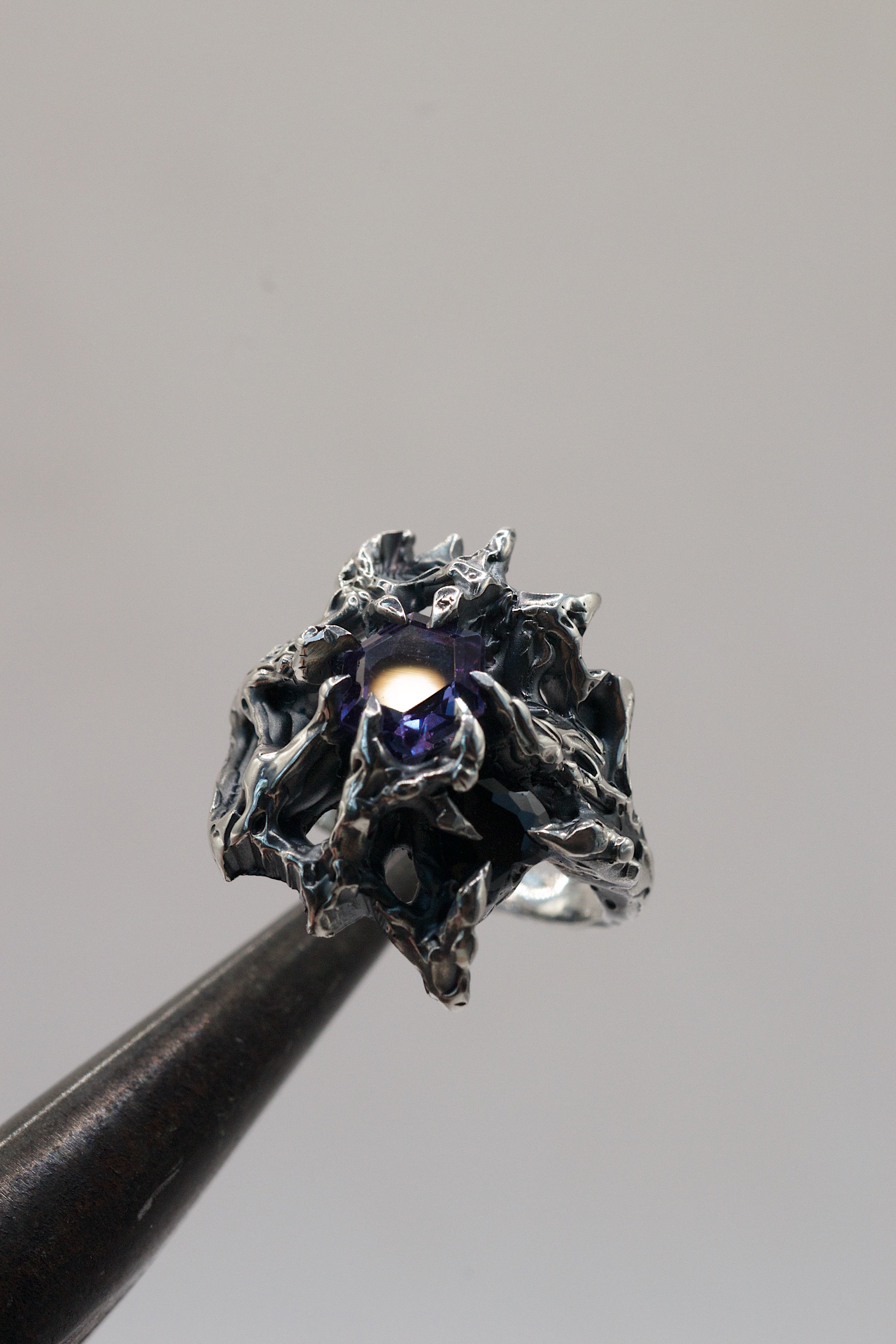 Grunge-inspired silver ring with ten sculpted claws gripping a heart-shaped crystal and hex-cut lab-grown alexandrite.