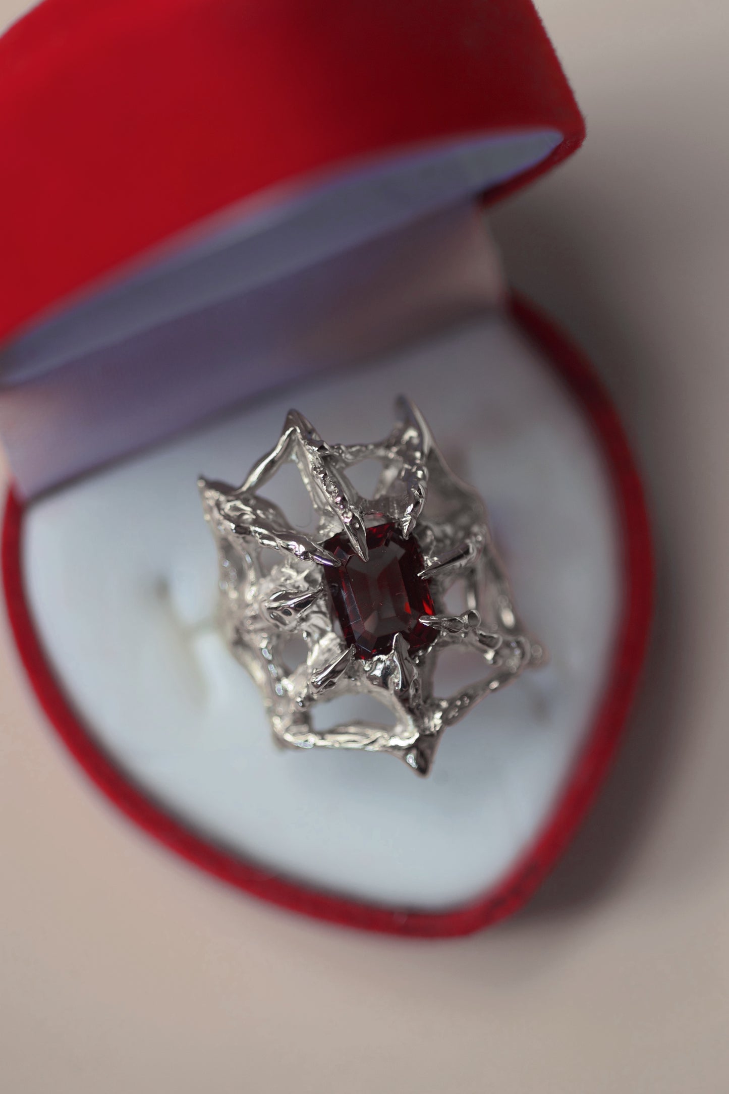 lost wax organic gothic style lost wax cast sterling silver ring with a spider web holding a garnet emerald cut lab grown nano crystal. handcrafted using the lost wax method. 