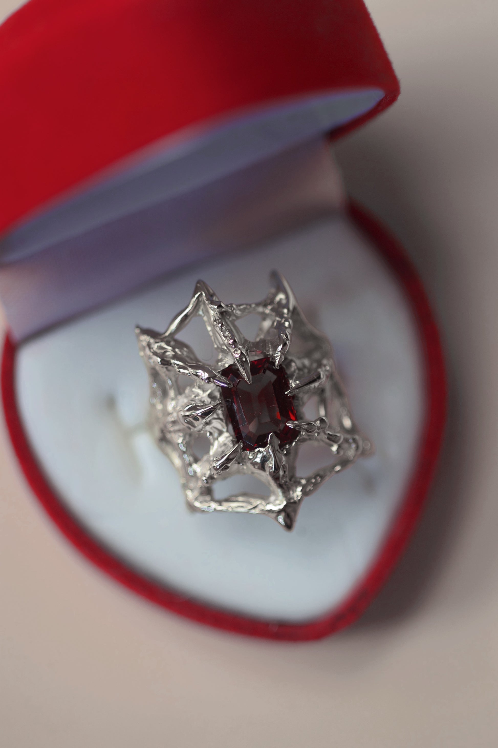 lost wax organic gothic style lost wax cast sterling silver ring with a spider web holding a garnet emerald cut lab grown nano crystal. handcrafted using the lost wax method. 