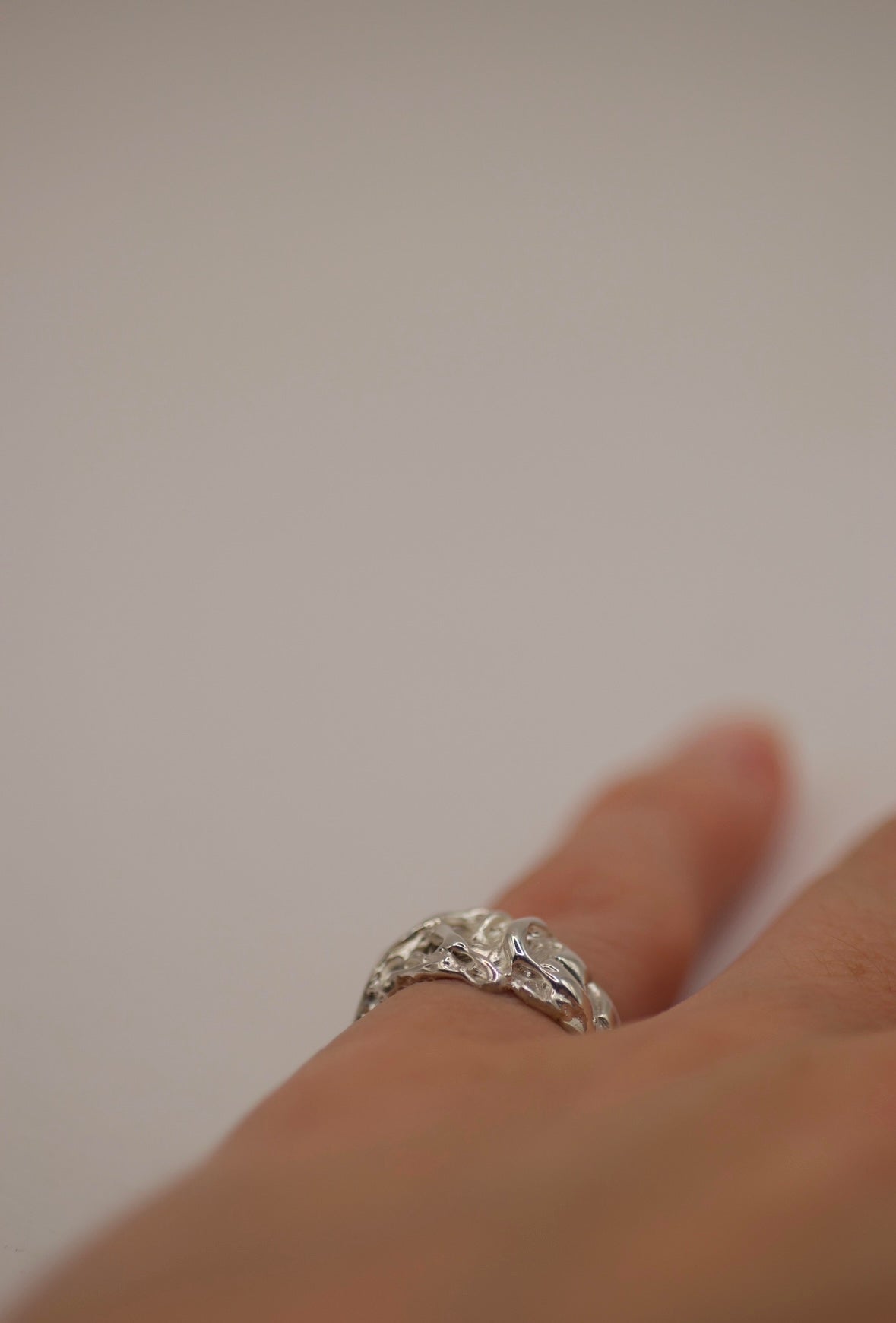 Handcrafted sterling silver band with a fluid, molten appearance. The ring’s surface features a dynamic, drippy texture, with irregular lines and subtle indentations that create a raw, unrefined aesthetic - on hand.