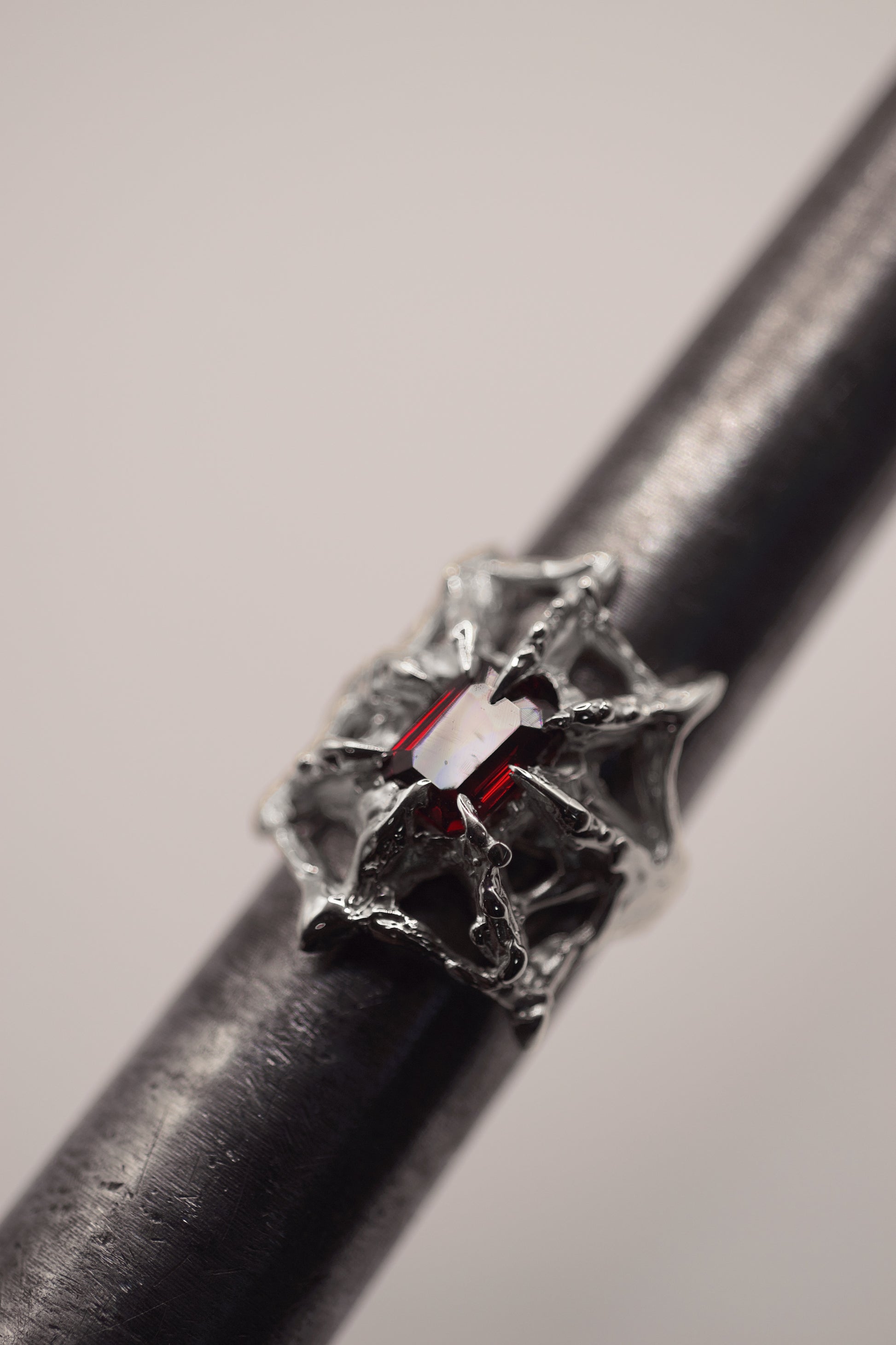 alternative gothic style lost wax cast sterling silver ring with a spider web holding a garnet emerald cut lab grown nano crystal. handcrafted using the lost wax method. 