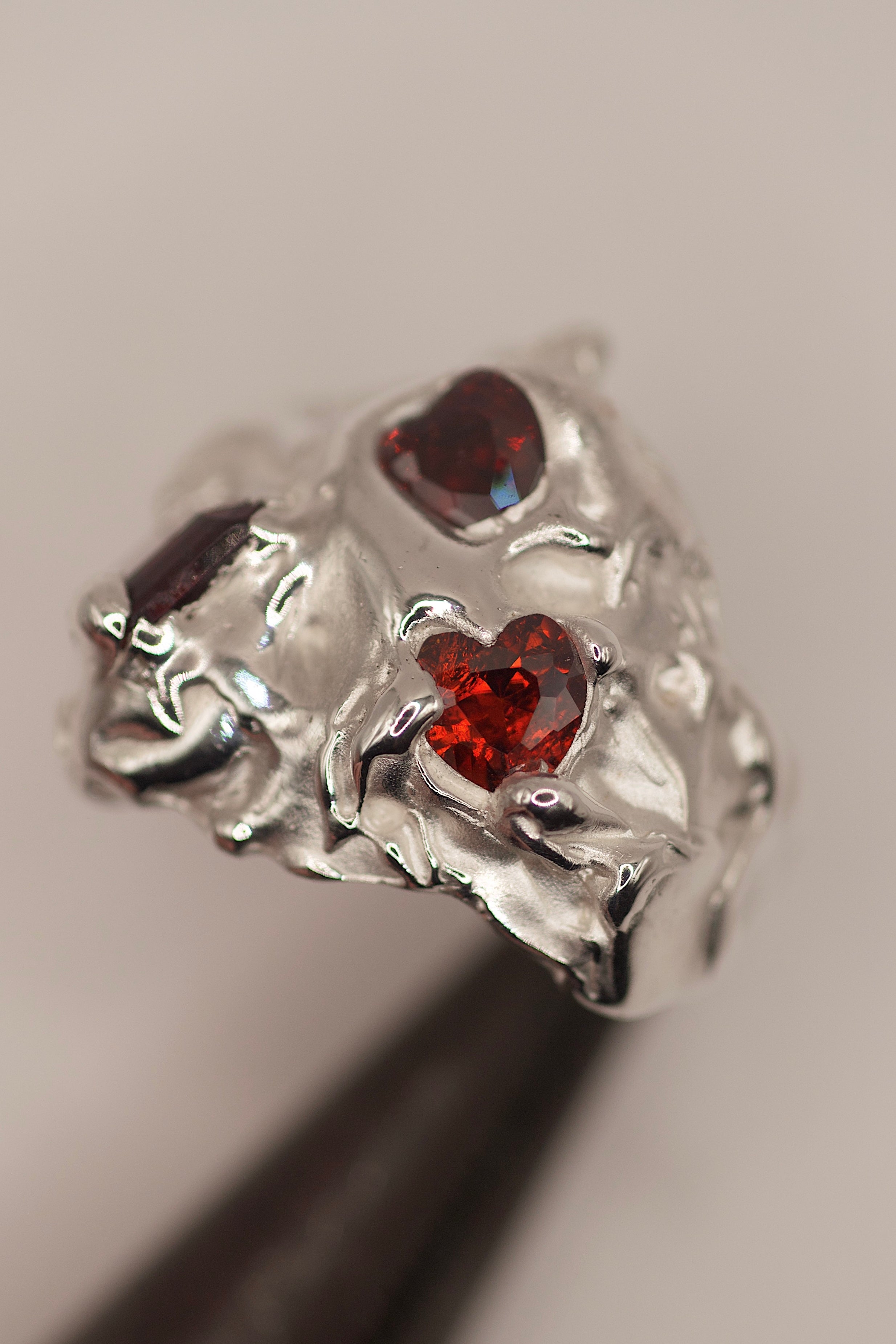 Handmade lost wax cast sterling silver ring with red lab-grown garnet and two red heart cubic zirconias set within organic flowing molten silver, bold sculptural statement ring made using the wax carving technique
