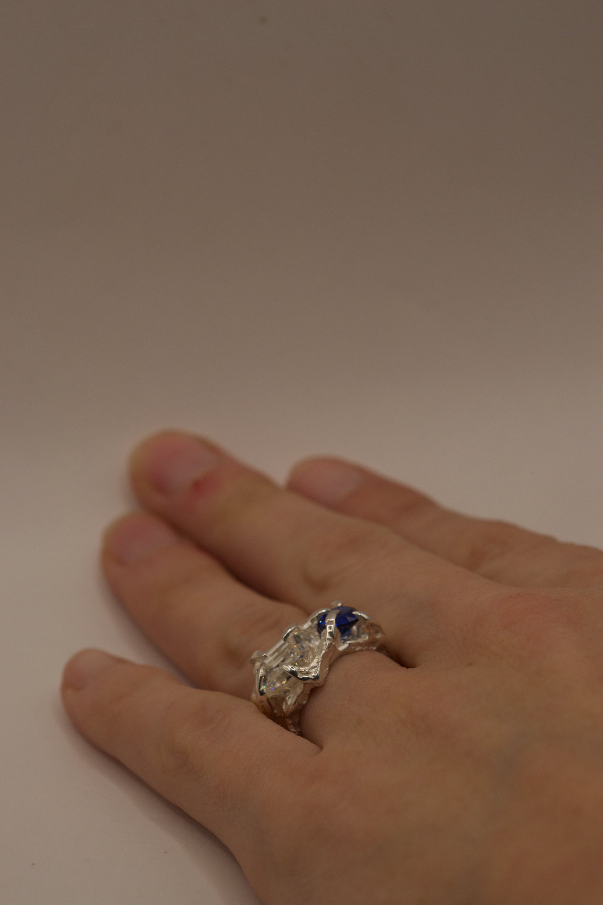 Organic sterling silver sapphire and moissanite ring on ring finger.