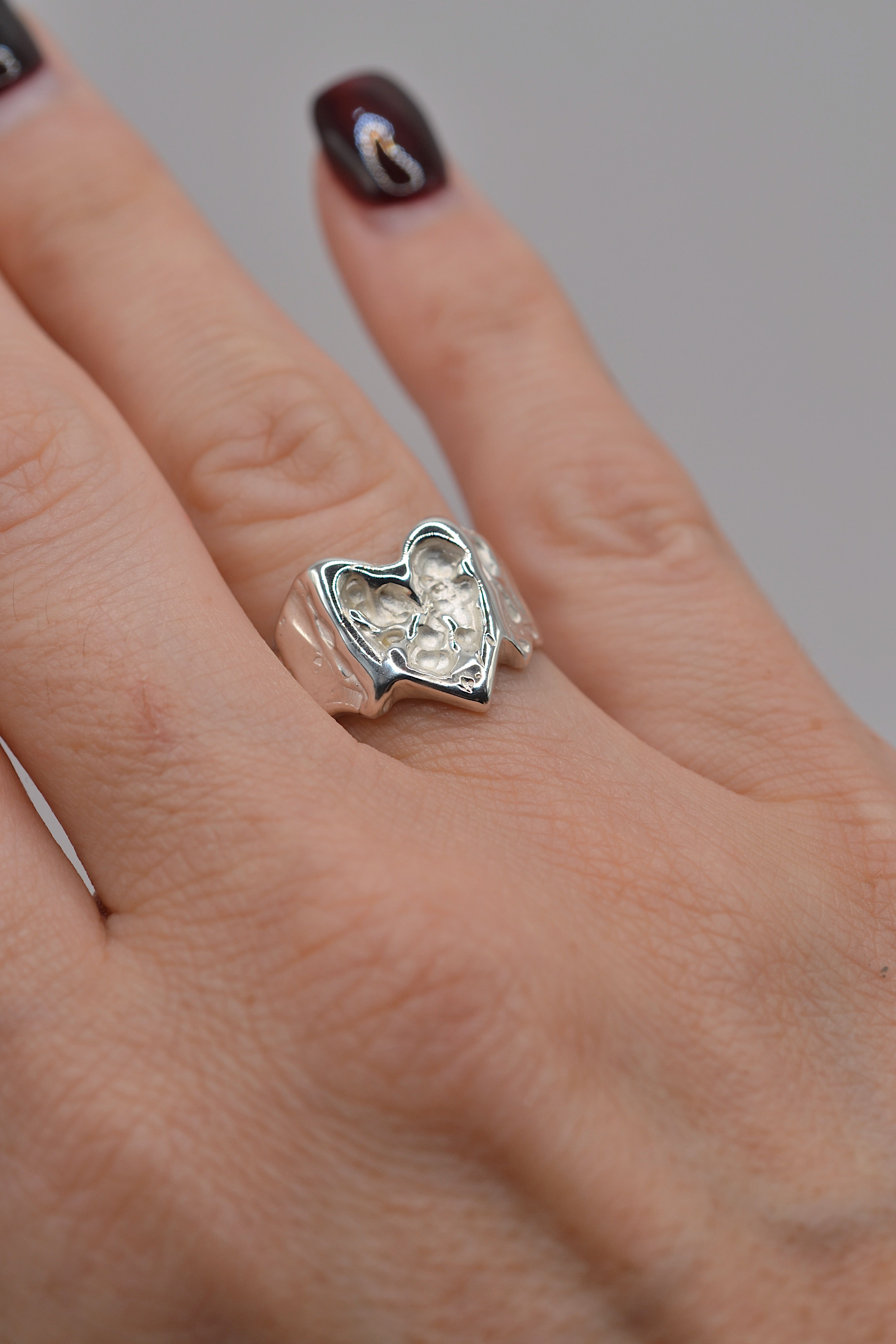 Lost wax cast silver Bleeding Heart Ring worn on hand with sculptural heart detail and organic flowing sterling silver band