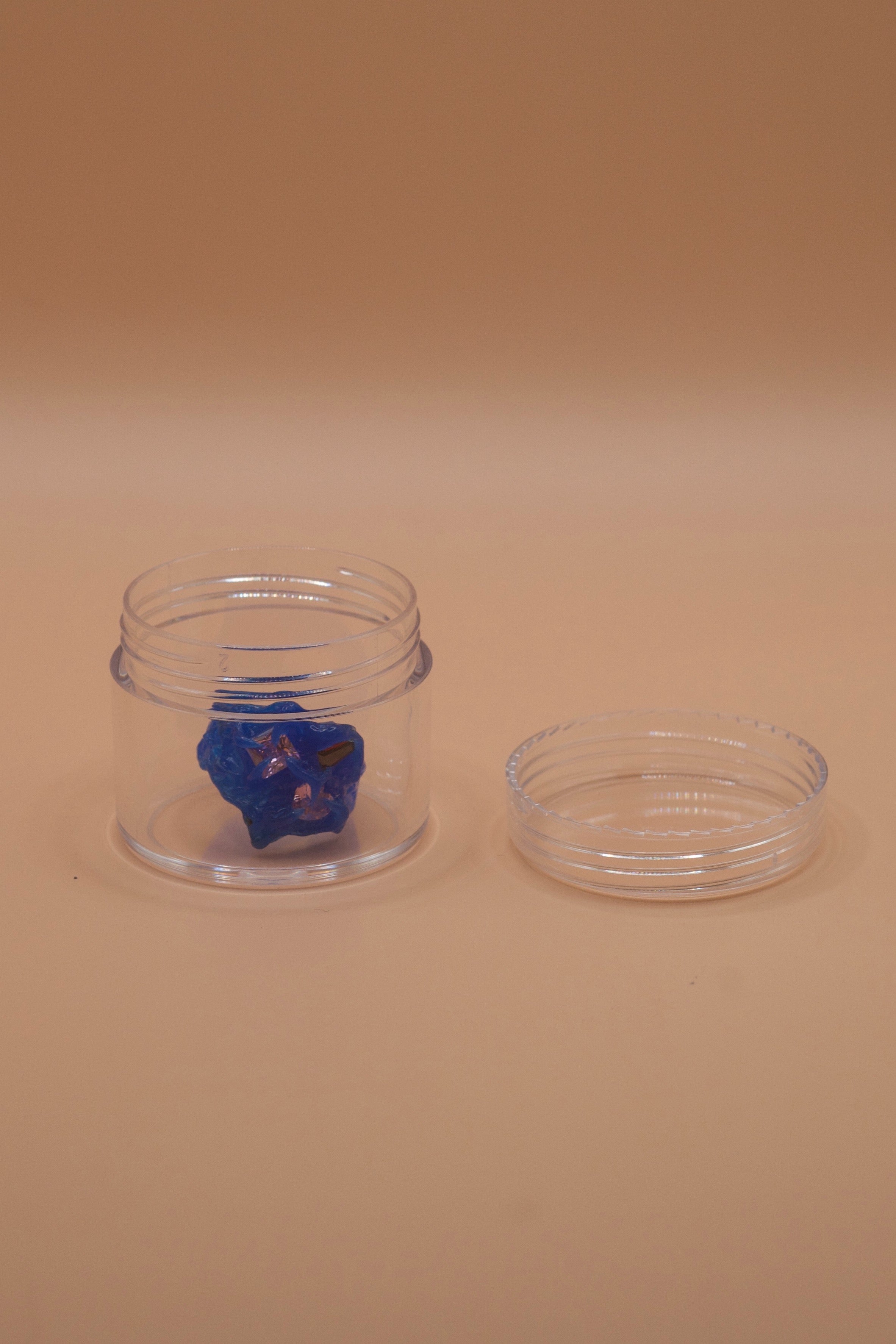 One clear jar holding a blue wax jewellery model, lid placed beside it. Ideal for sending wax design to a casting facility.