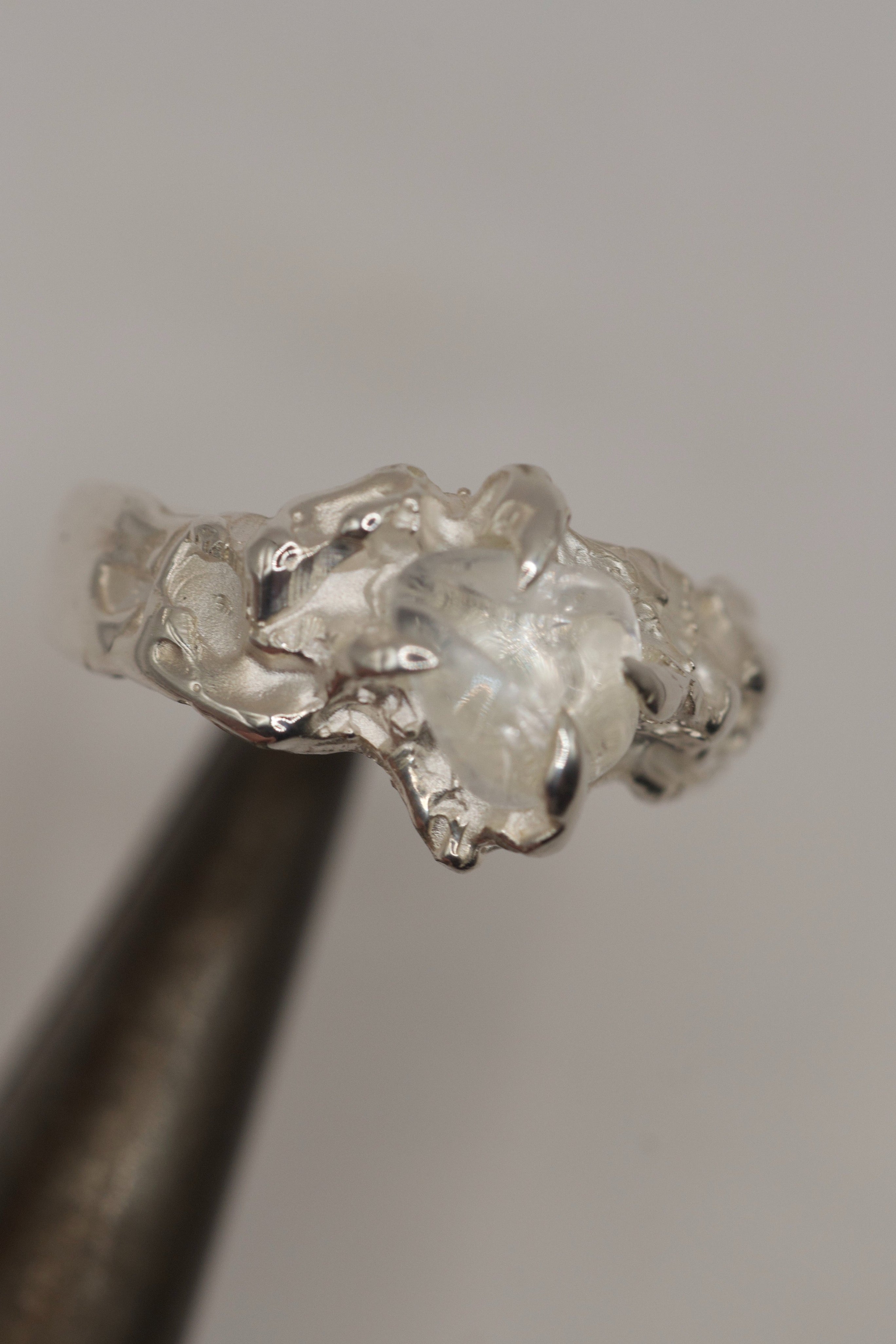 Cloud Nine Ring held in tweezers showing natural clear quartz set within soft organic flowing sterling silver handmade using the lost wax technique