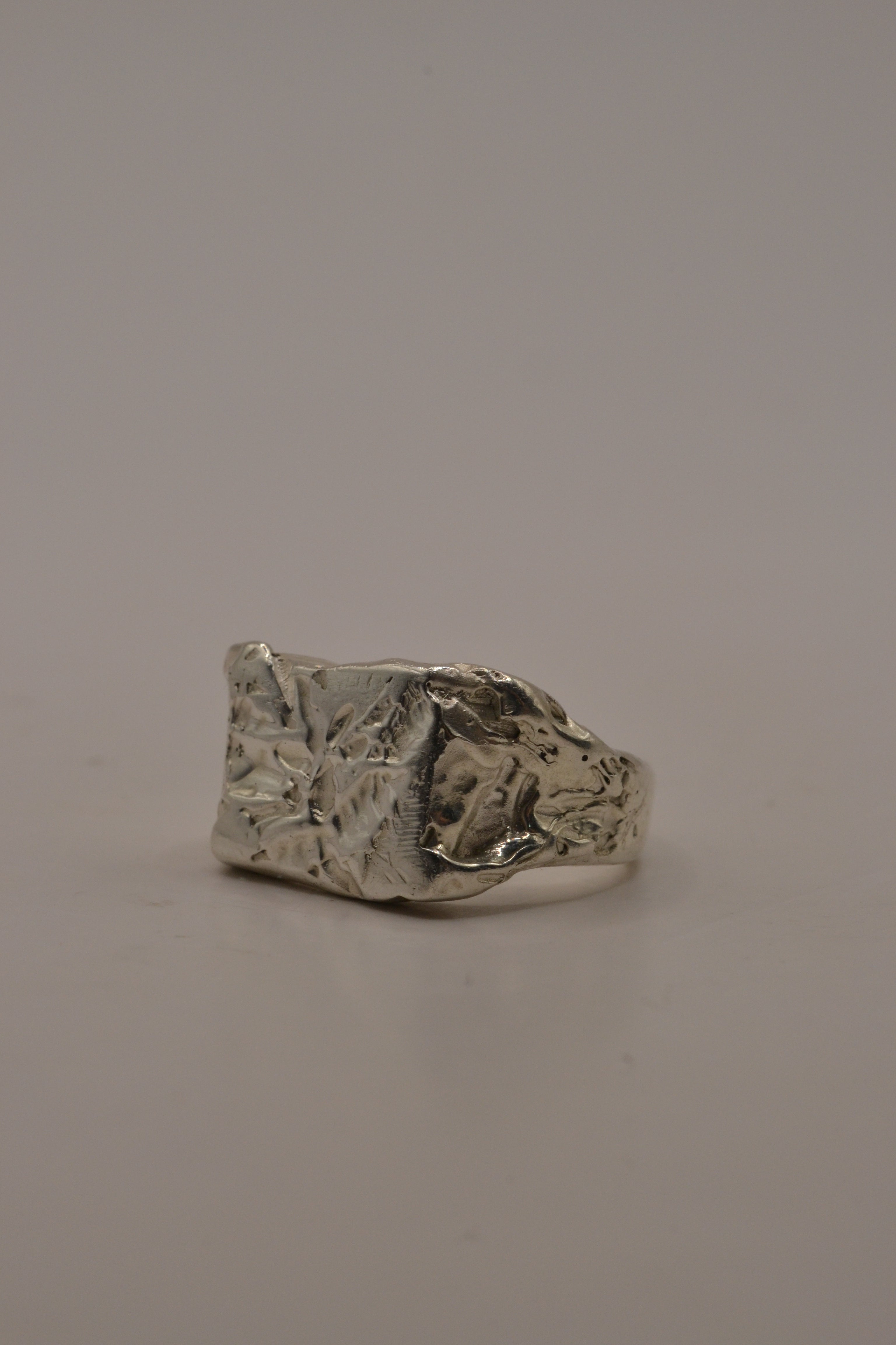 Handmade lost wax cast sterling silver alternative signet ring with raw concrete-like texture across the square face, minimal sculptural ring made using the wax carving technique
