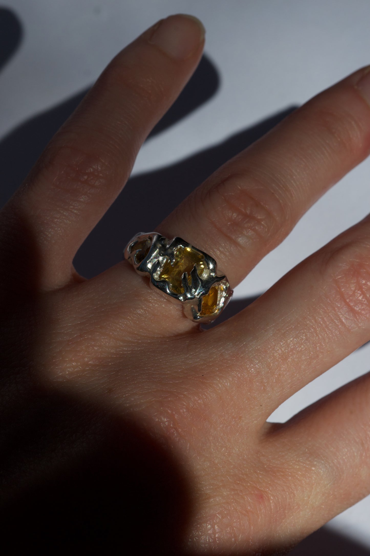 Sterling silver ring with fancy-cut yellow gemstones on fingers.
