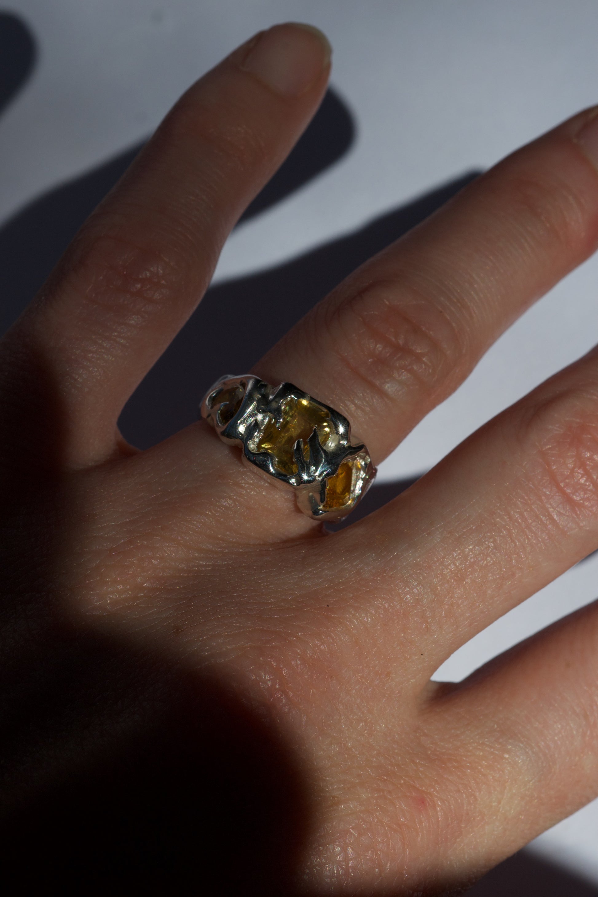Sterling silver ring with fancy-cut yellow gemstones on fingers.