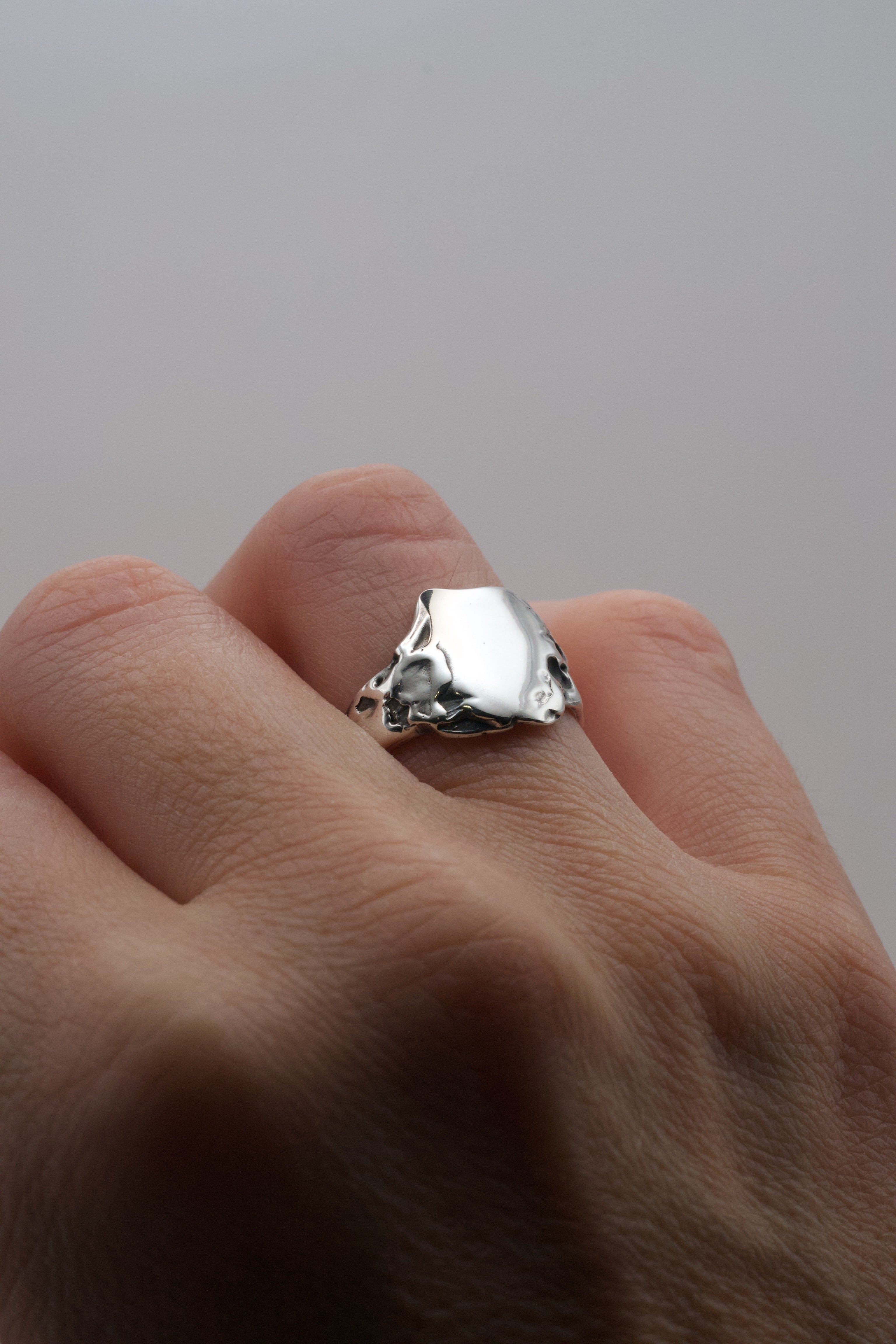 Flat lay of the Duality Ring showing darkened sterling silver signet form and dimensional organic molten texture lost wax cast