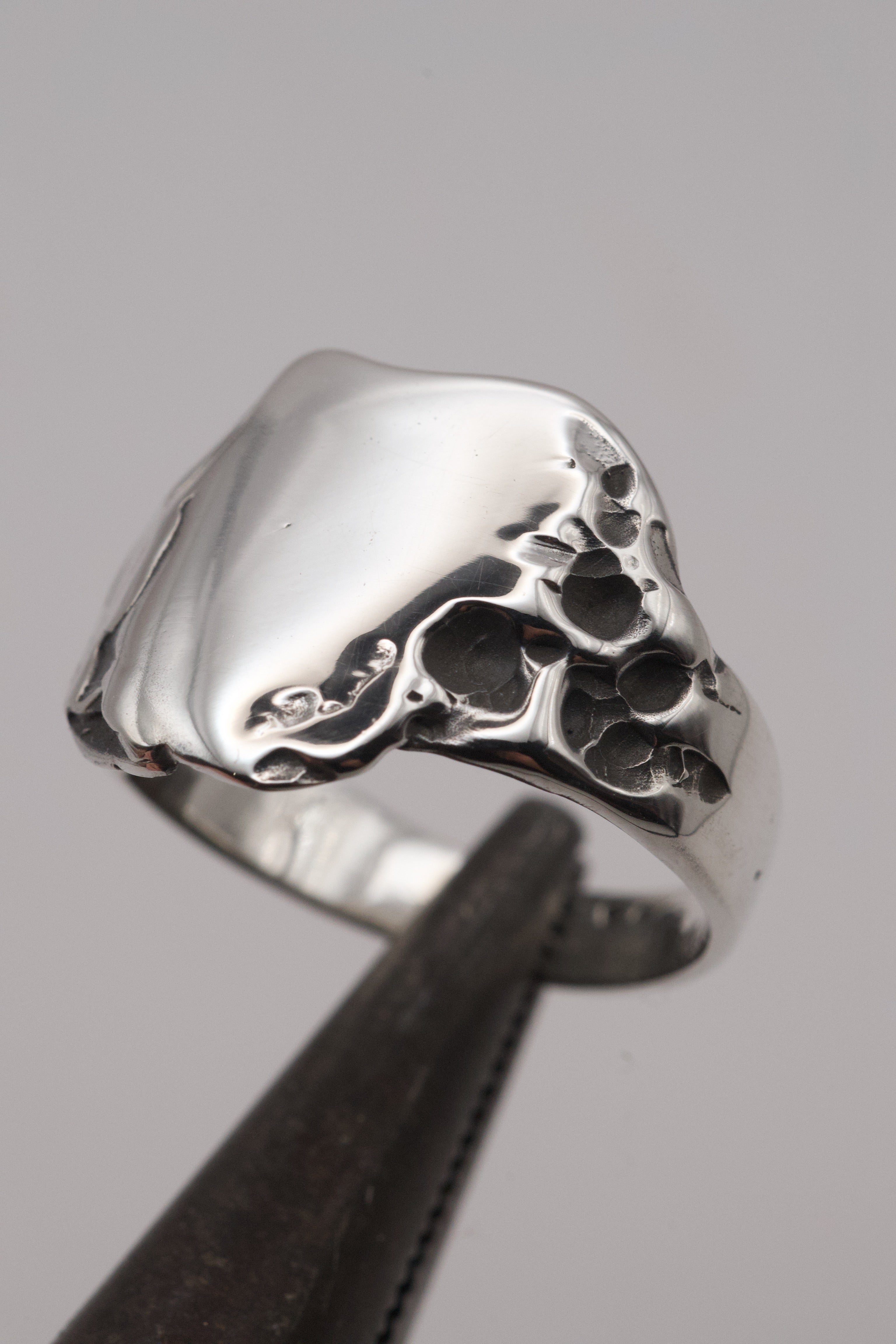 Side angle of the Duality Ring worn on hand showing darkened sterling silver signet form and raw sculptural texture