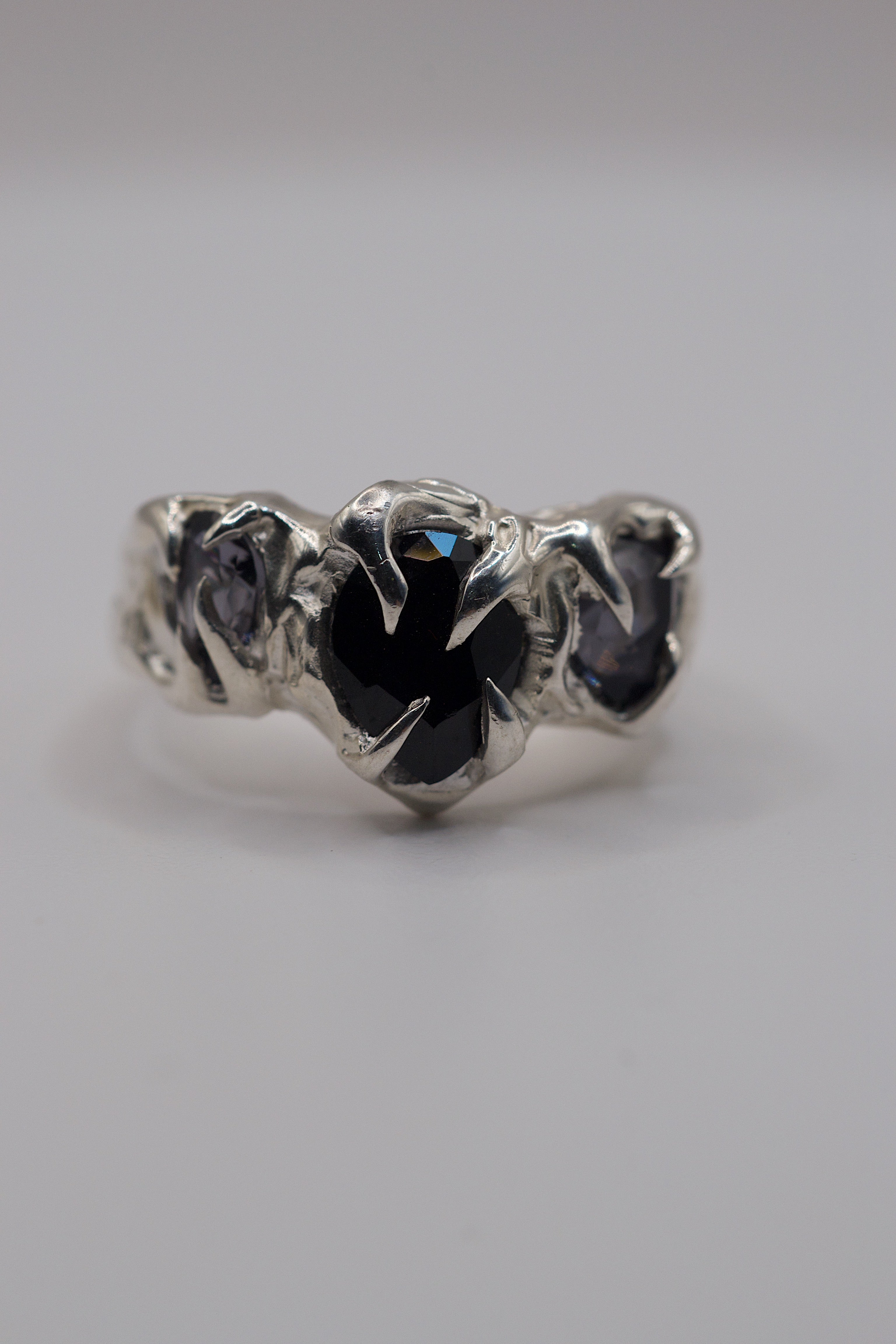Sterling silver ring with gothic claws holding a pear cut onyx gemstone and lab-grown spinels.