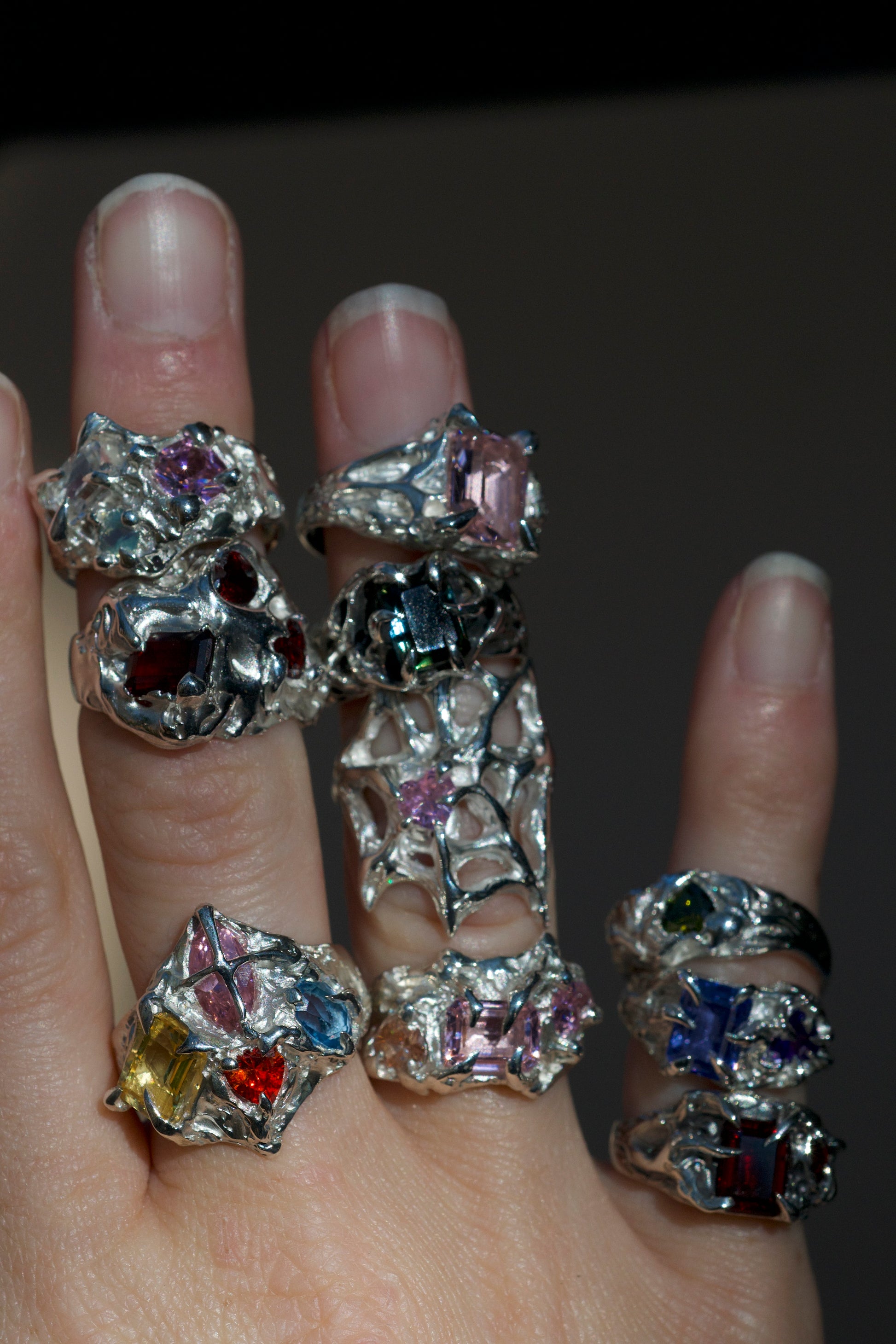 Silver ring with colorful gemstones on a gray background. Organic gothic style claw ring with multiple gemstones handmade with lost wax on fingers.