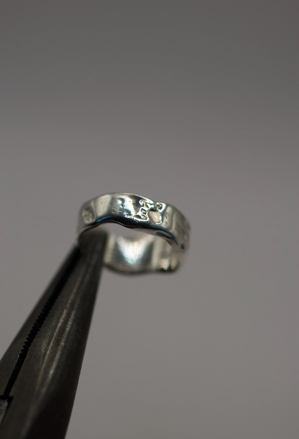 Handmade lost wax cast sterling silver ring held in tweezers, created during a wax carving jewellery making workshop on the Sunshine Coast