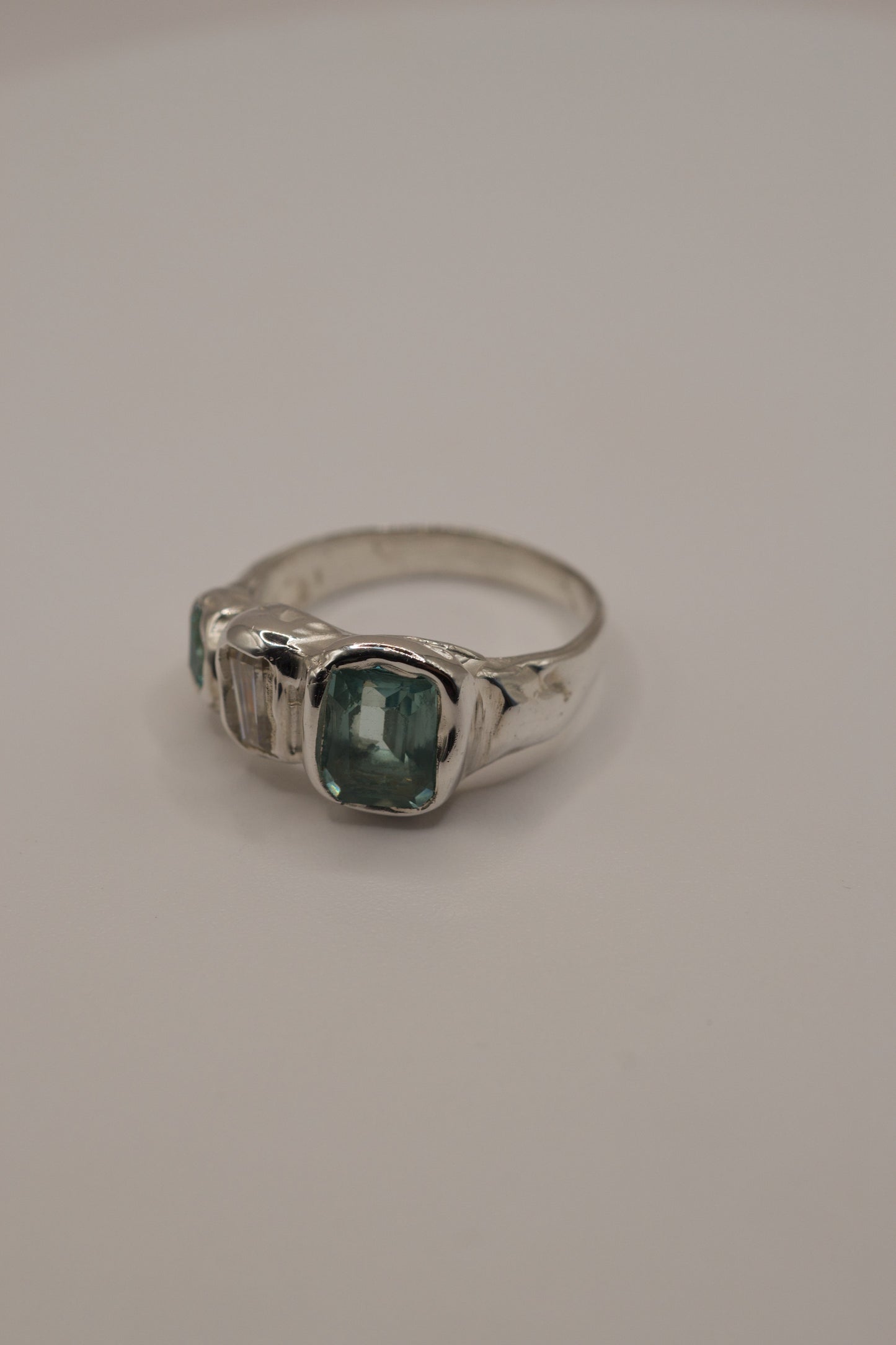 Organic molten 925 sterling silver ring with a high polish finish, featuring a central square-cut seafoam green gemstone, baguette-cut sparkling moissanite, and an additional green-toned crystal, handmade with cast in place gemstones using the lost wax casting process.