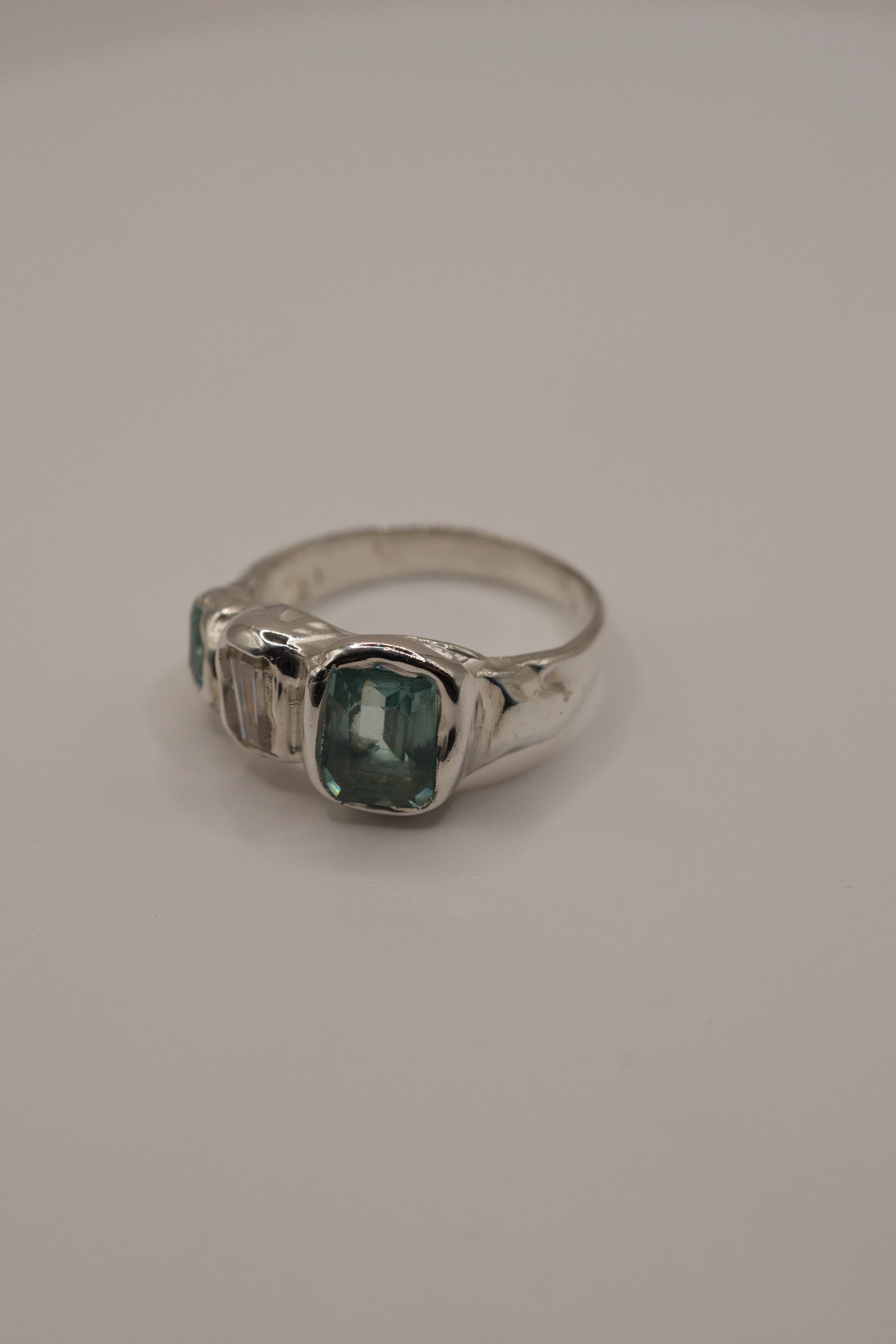 Organic molten 925 sterling silver ring with a high polish finish, featuring a central square-cut seafoam green gemstone, baguette-cut sparkling moissanite, and an additional green-toned crystal, handmade with cast in place gemstones using the lost wax casting process.