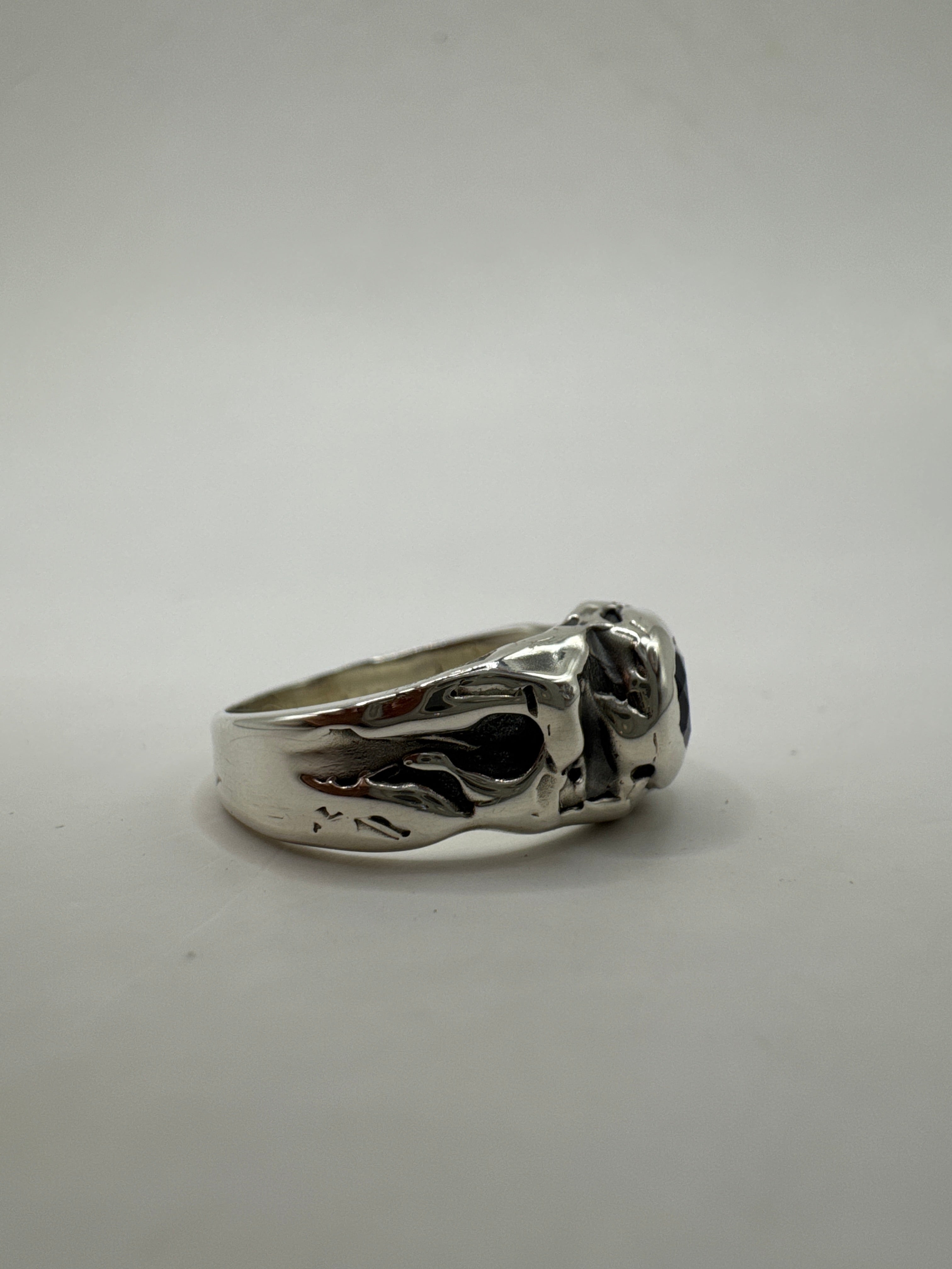  Midnight Ring laid flat on neutral background. Deep blue sapphire set in recycled 925 silver with dark patina and organic lost wax texture.