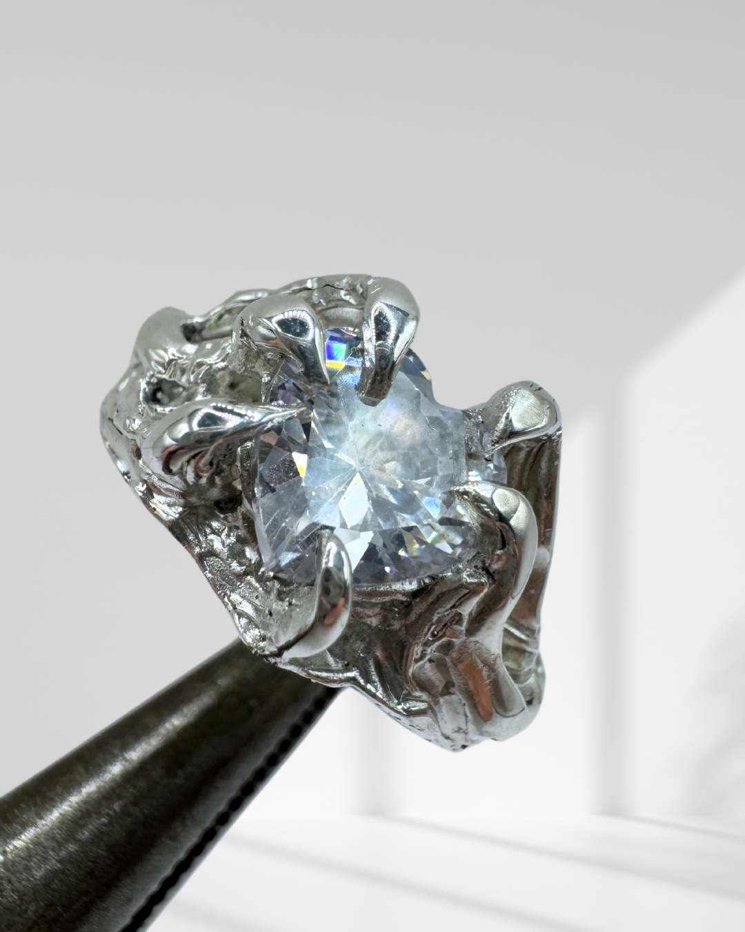 Molten and organic textured gothic ring in sterling silver with a heart-shaped crystal, 6 claw prongs, and handcrafted using the lost wax carving method.