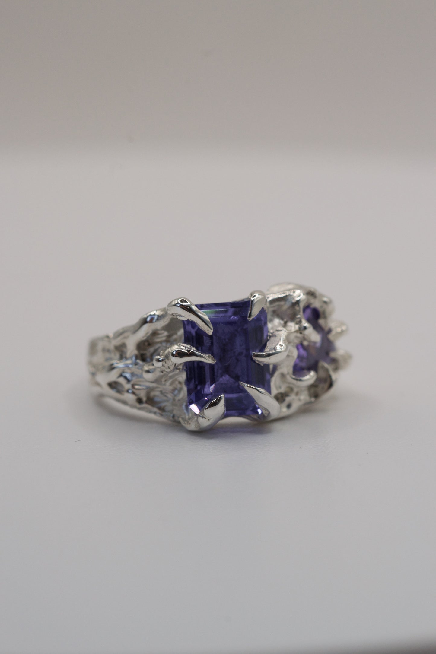 Silver ring with a purple gemstone on a gray background