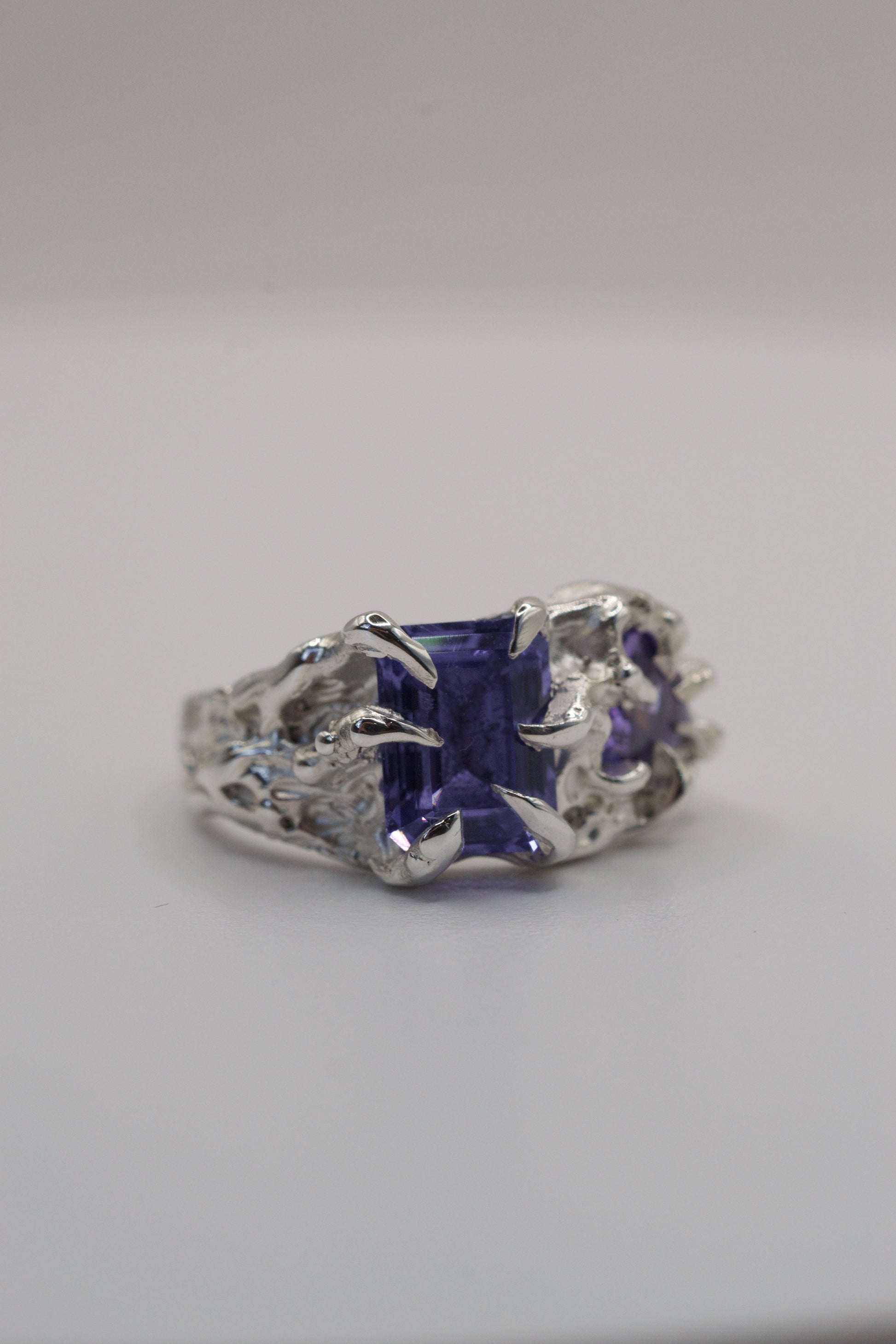 Silver ring with a purple gemstone on a gray background