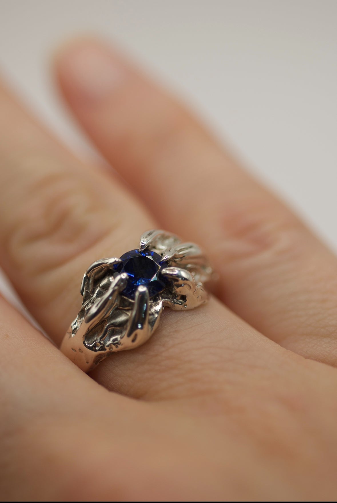 Lost wax cast darkened sterling silver Raven Ring worn on hand with vibrant gemstone and organic heavily textured patina setting