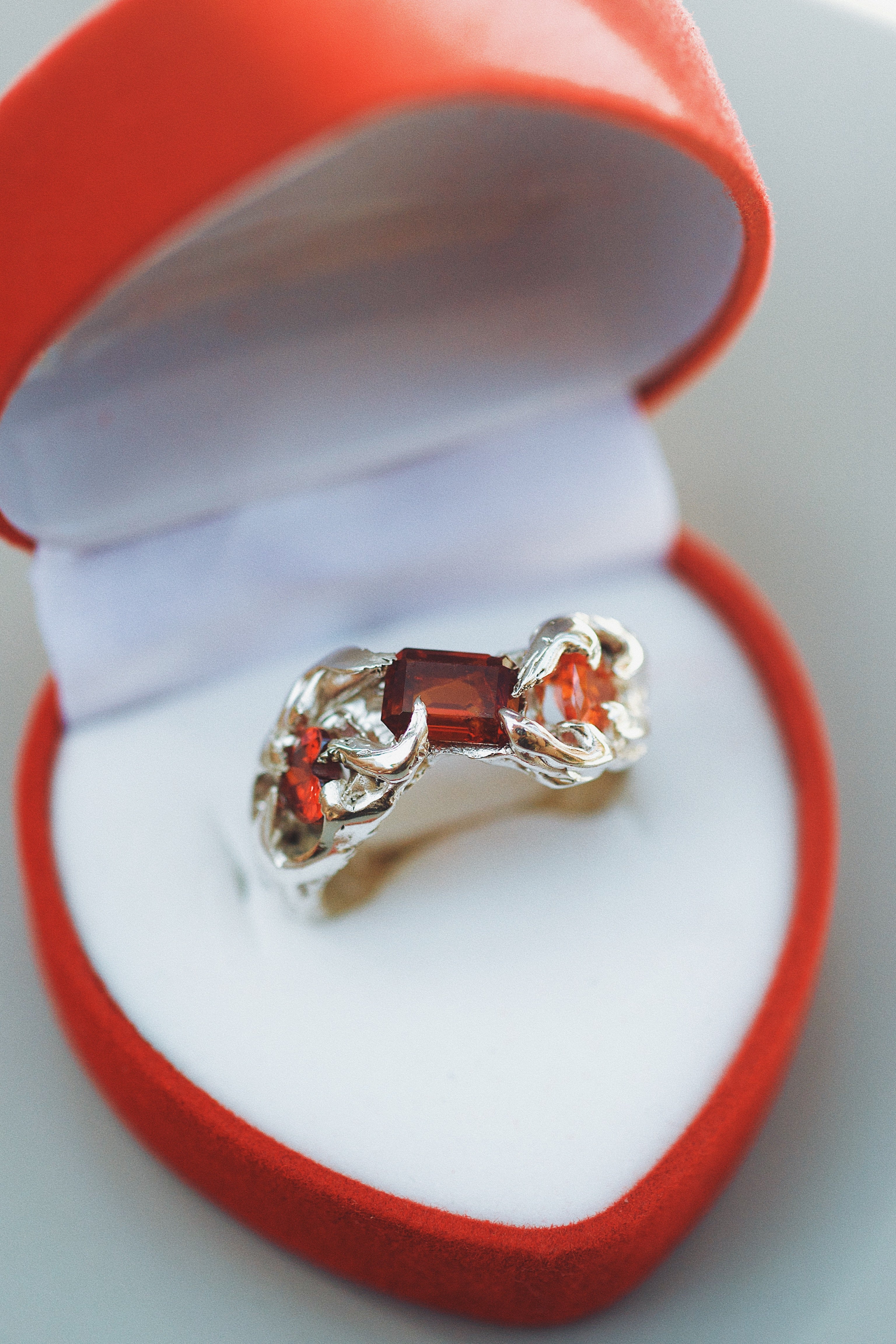 Lost wax cast silver Rendezvous Ring in ring box with red garnet and organic flowing silver setting handmade alternative jewellery