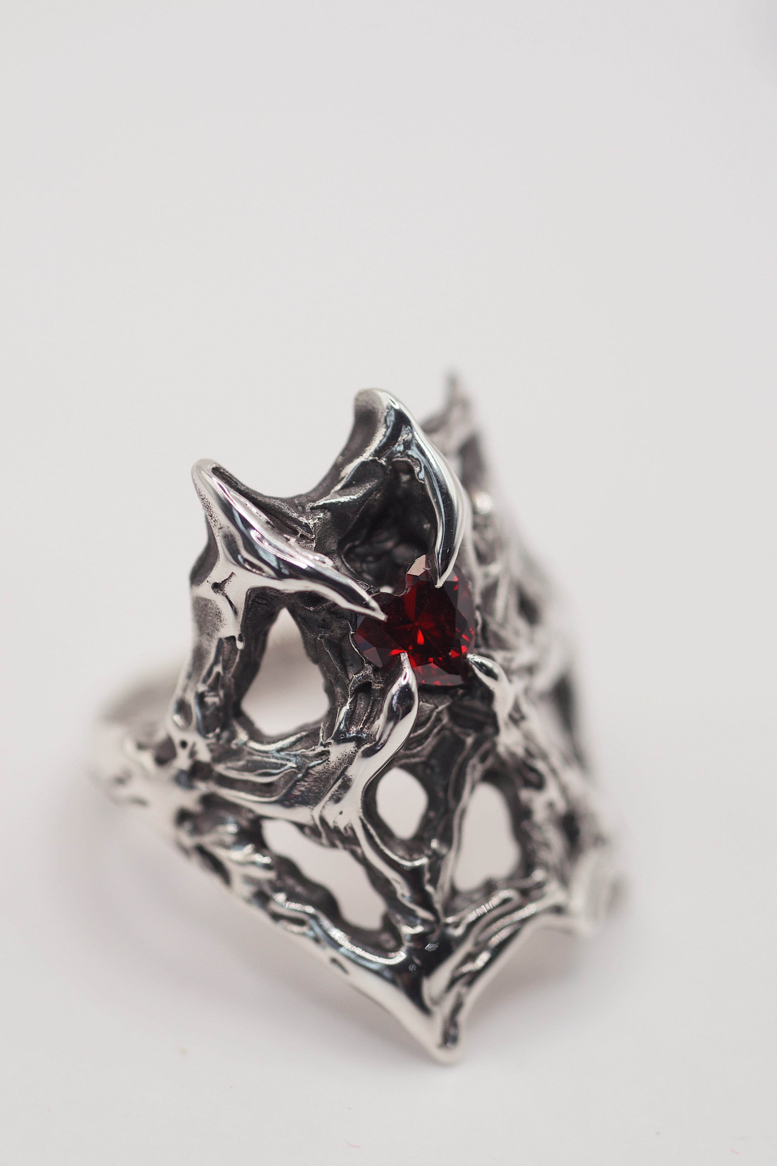 Lost wax cast darkened sterling silver Scarlet Ring worn on hand with intricate web structure and lab-grown red garnet heart